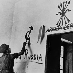 A member of the Internatinal Brigade applies some of his propaganda in a village wall