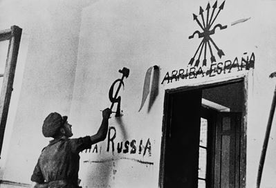 Robert Capa, Membro della Brigata Internazionale applica propaganda su una parete di villaggio, S...