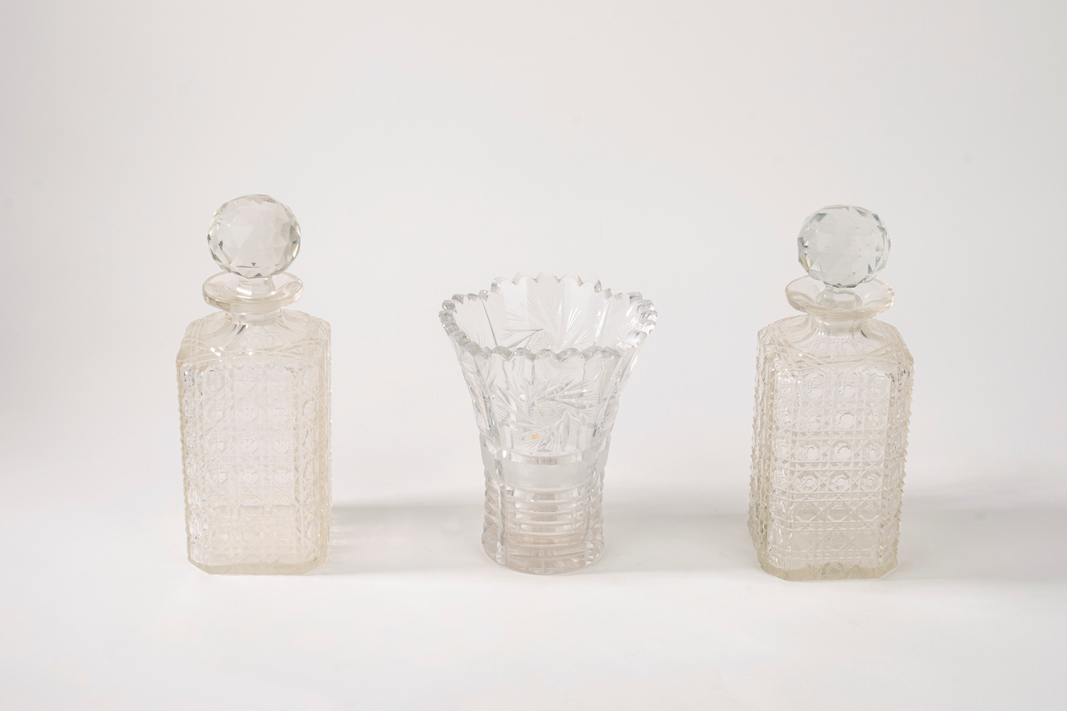 Coppia di bottiglie da liquore con tappo e un vaso portafiori in cristallo molato con decoro a mo...