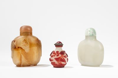 Cina, Gruppo di tre snuff bottles in agata, vetro incamiciato e giada