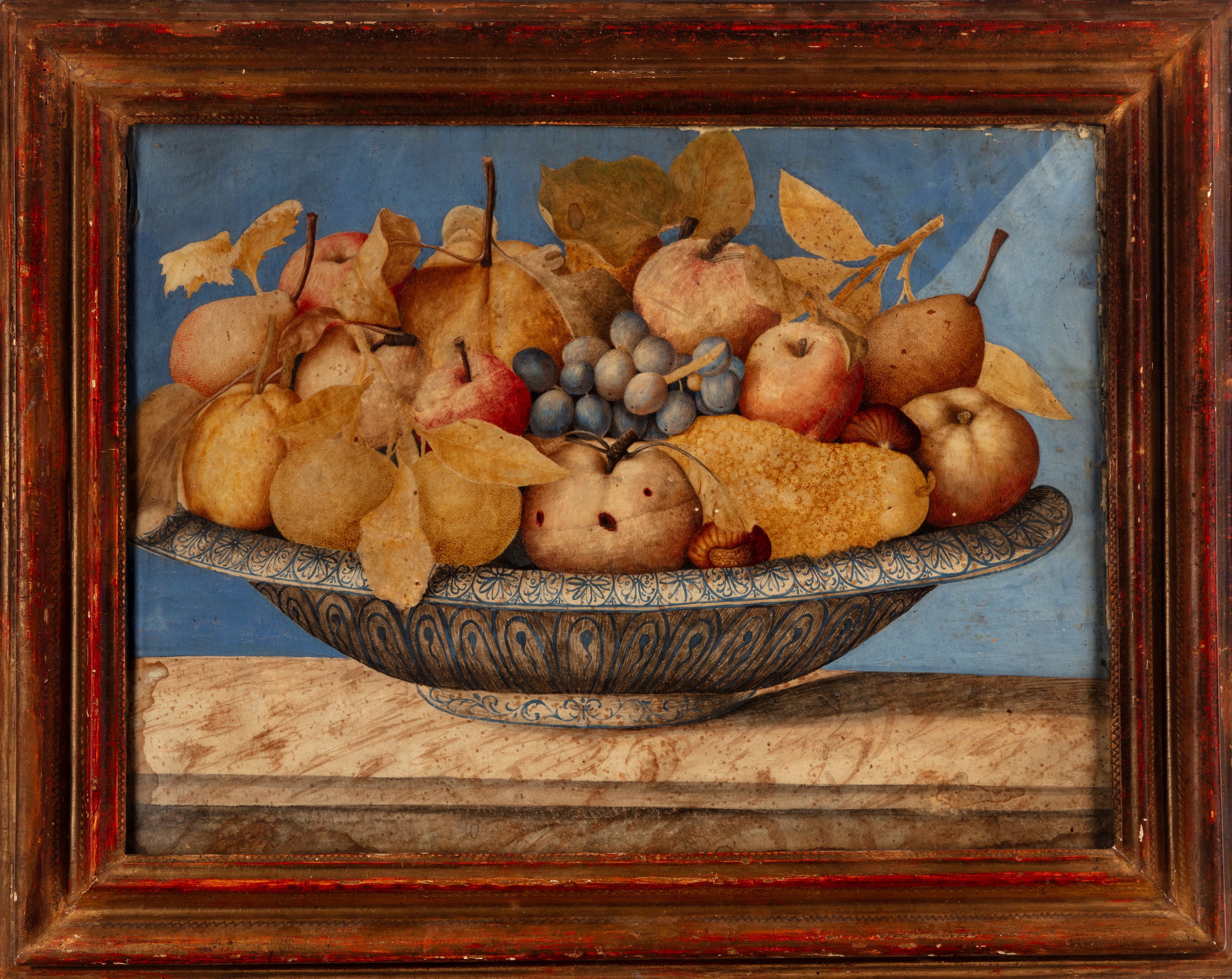 Mele, pere, uva, castagne e altri frutti in un'alzata di ceramica bianca e blu su un piano di pie...