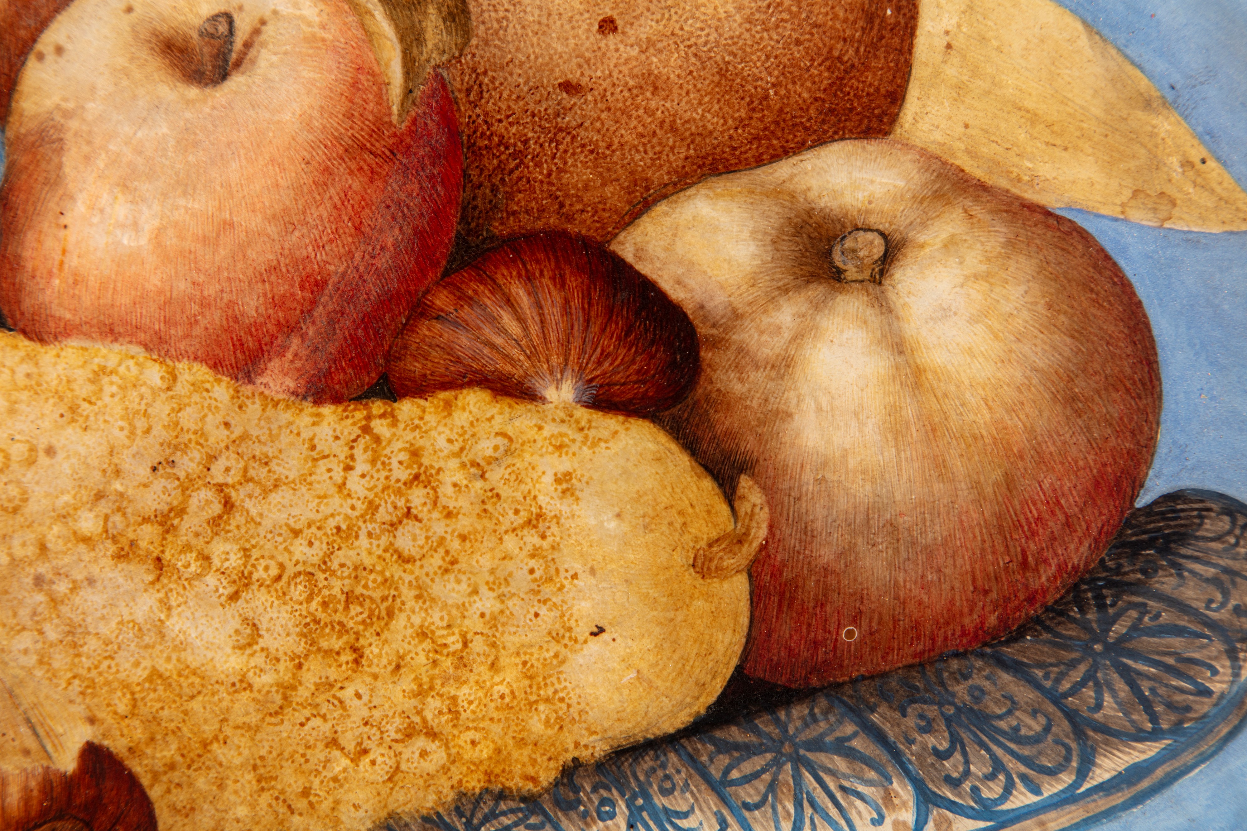 Mele, pere, uva, castagne e altri frutti in un'alzata di ceramica bianca e blu su un piano di pie...