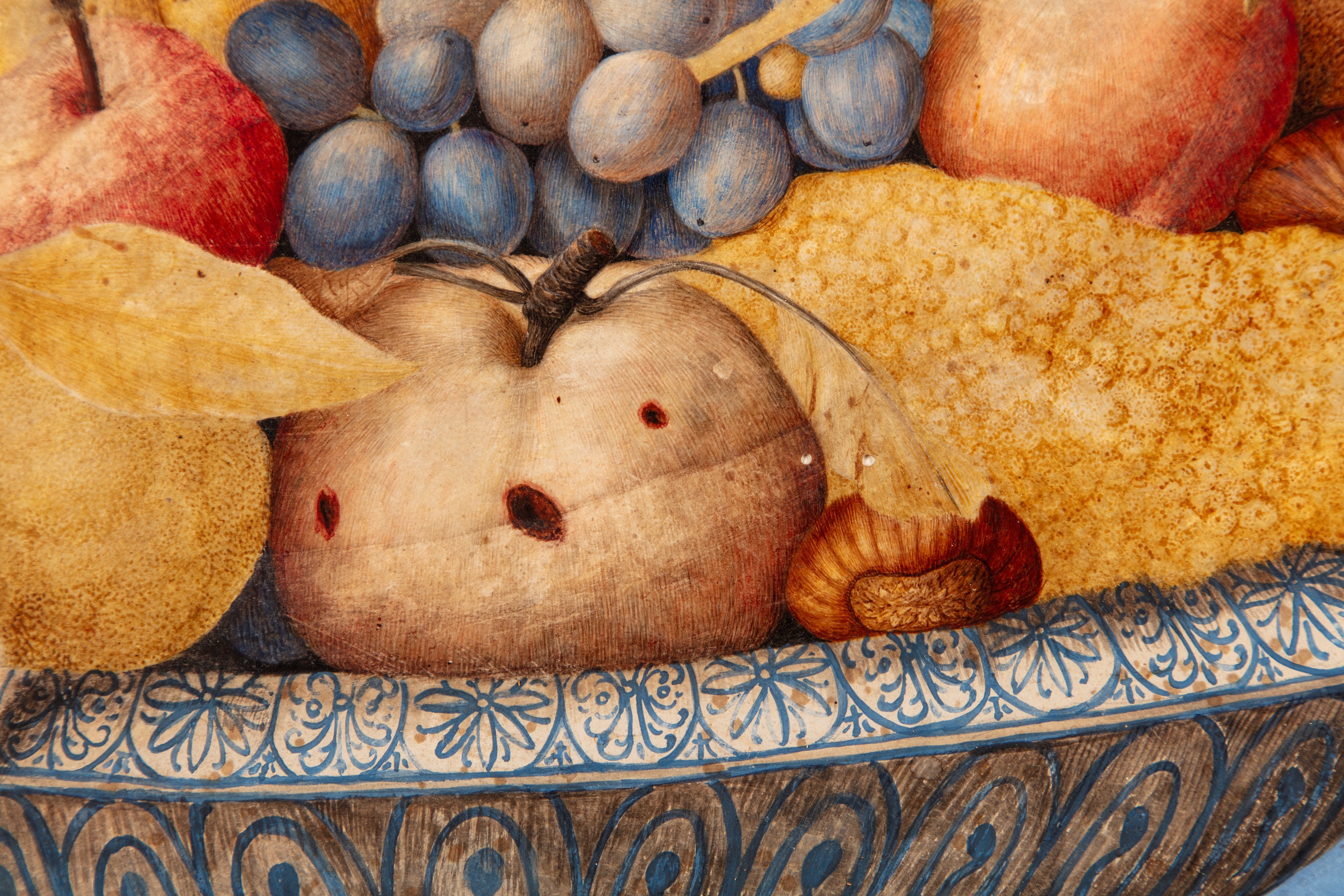 Mele, pere, uva, castagne e altri frutti in un'alzata di ceramica bianca e blu su un piano di pie...