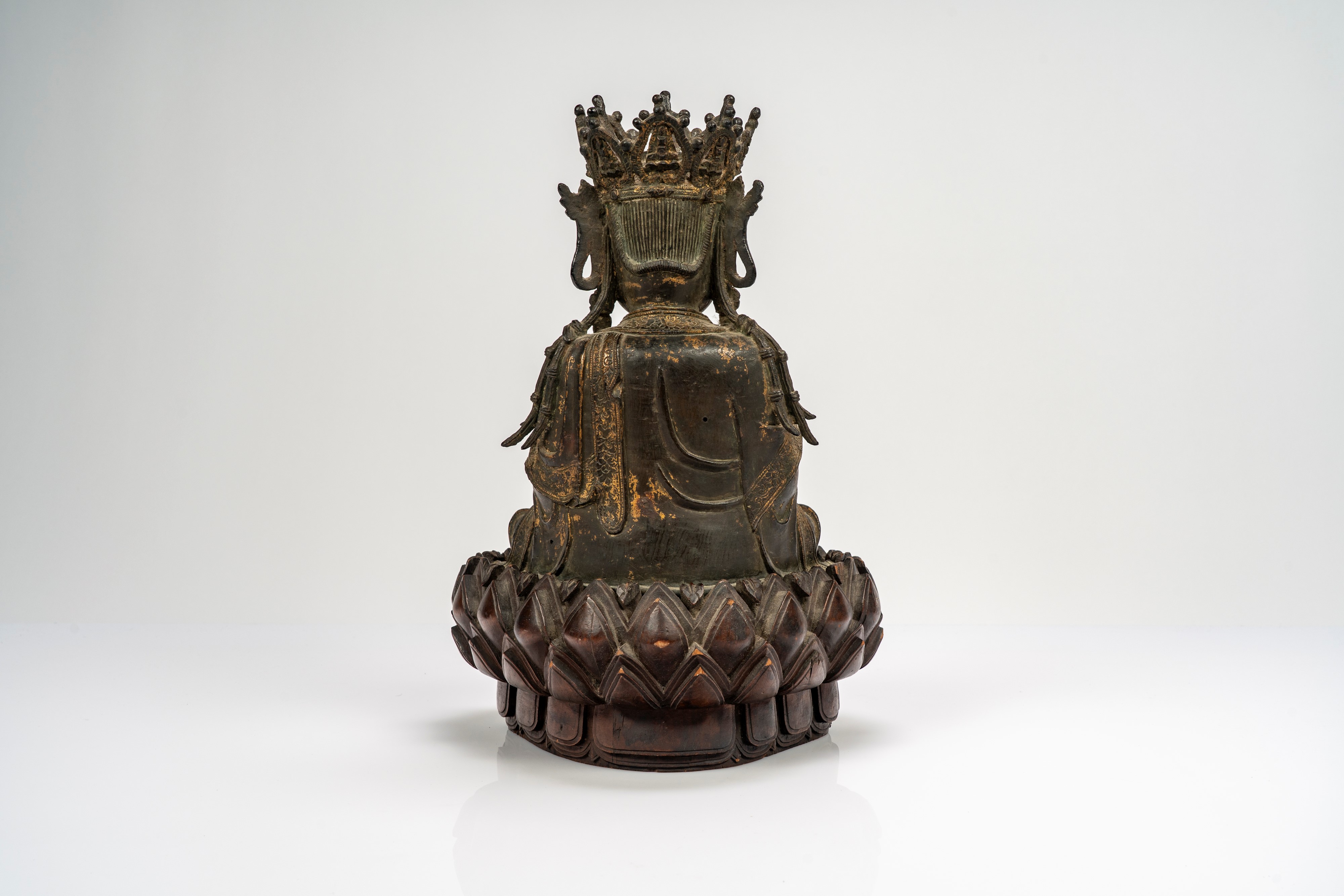 Guanyin in bronzo cesellato, con tracce di doratura, su base lignea a fiori di loto di epoca succ...