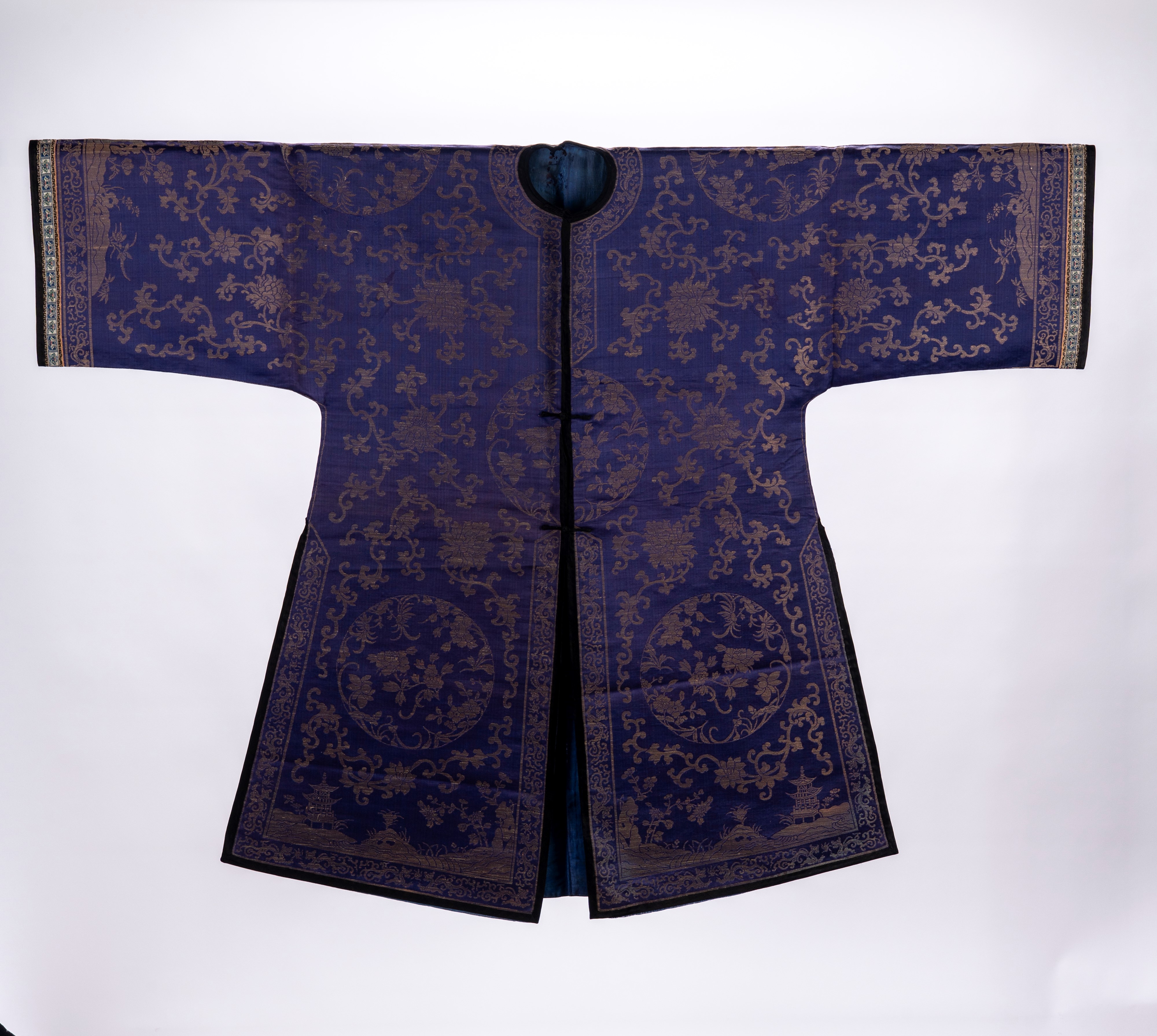 Lotto di due vesti in seta a fondo blu, una decorata con motivi floreali, ruyi e figure, l’altra ...