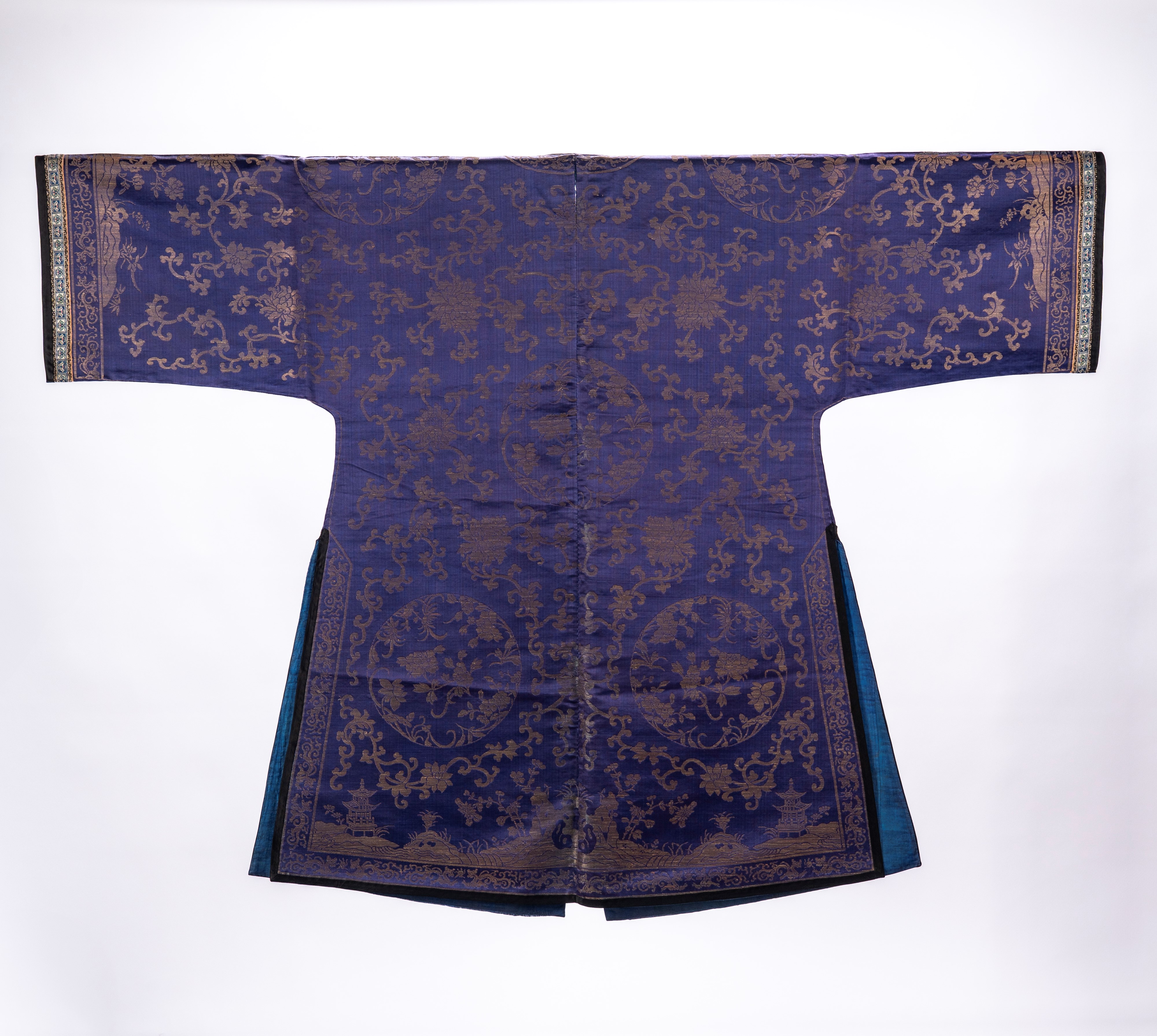 Lotto di due vesti in seta a fondo blu, una decorata con motivi floreali, ruyi e figure, l’altra ...