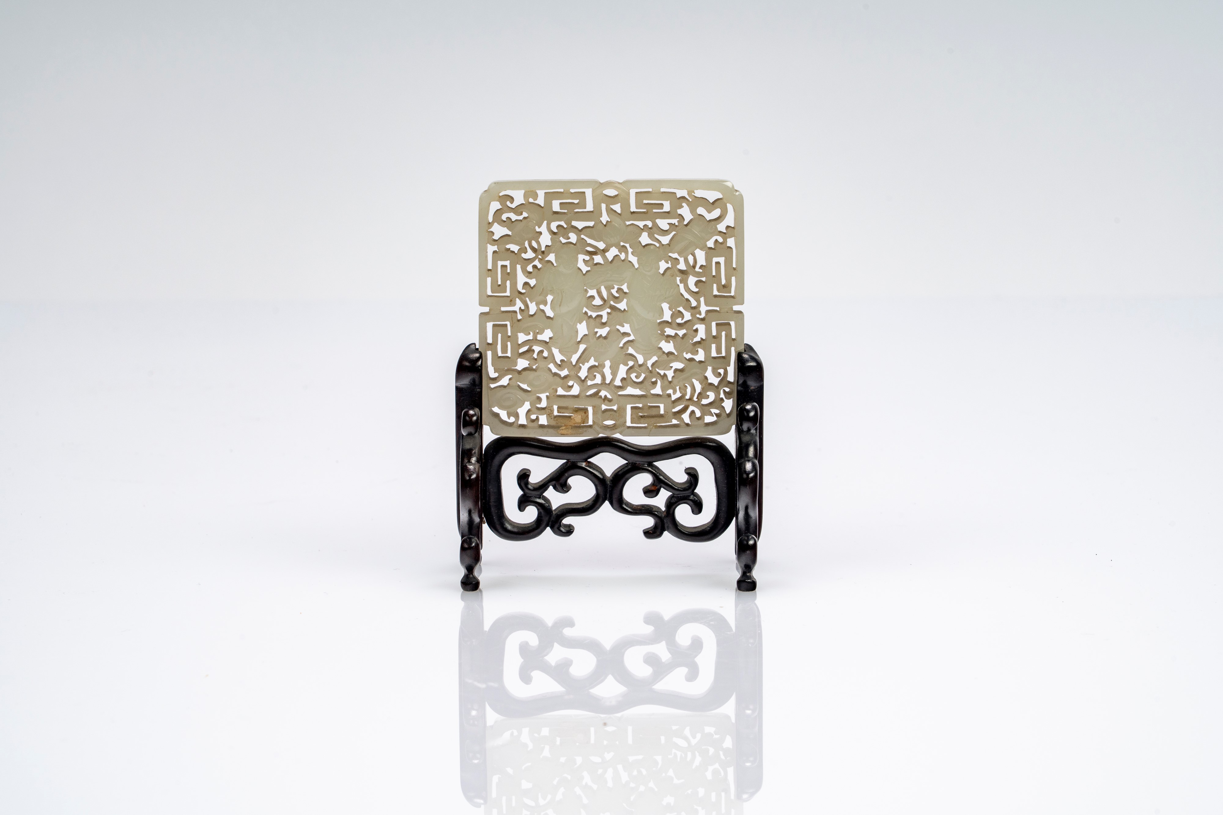 Placca in giada bianca traforata con figure e nuvole stilizzate, su base lignea. Cina, fine secol...