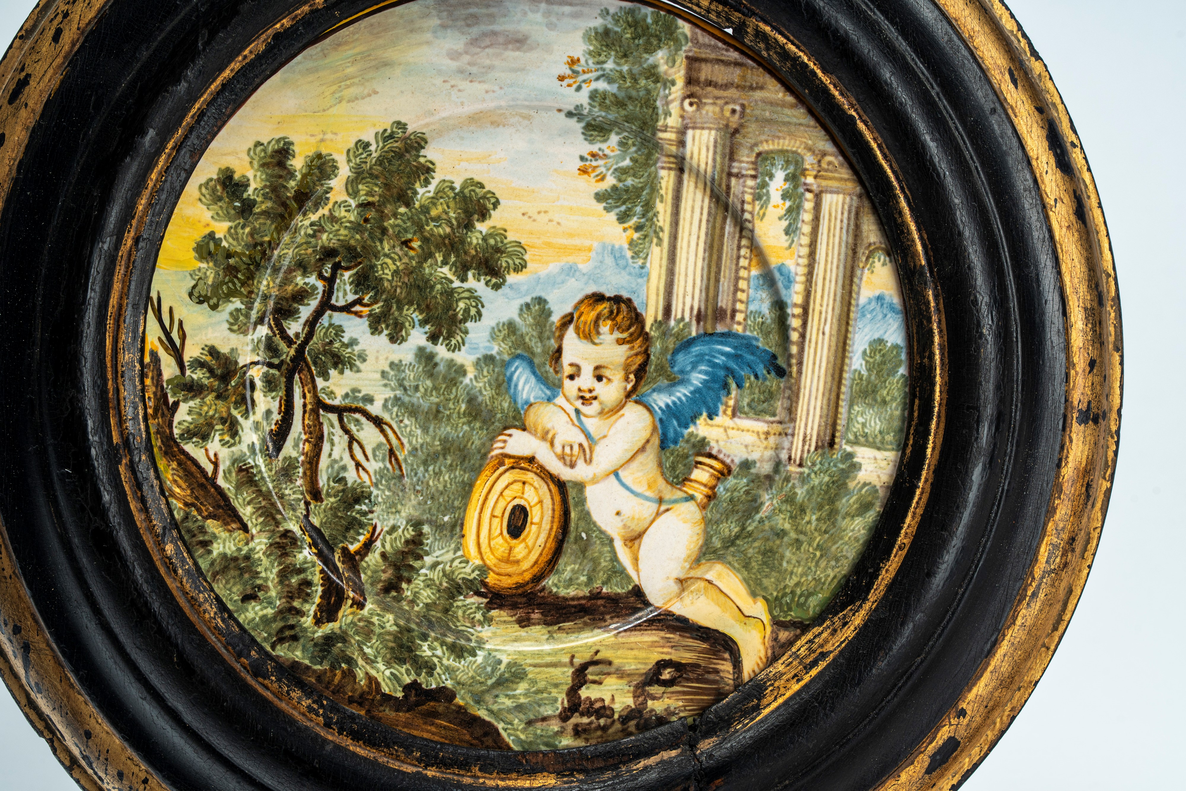 Piattello in maiolica policroma istoriata raffigurante putto alato con tamburo in un paesaggio ag...