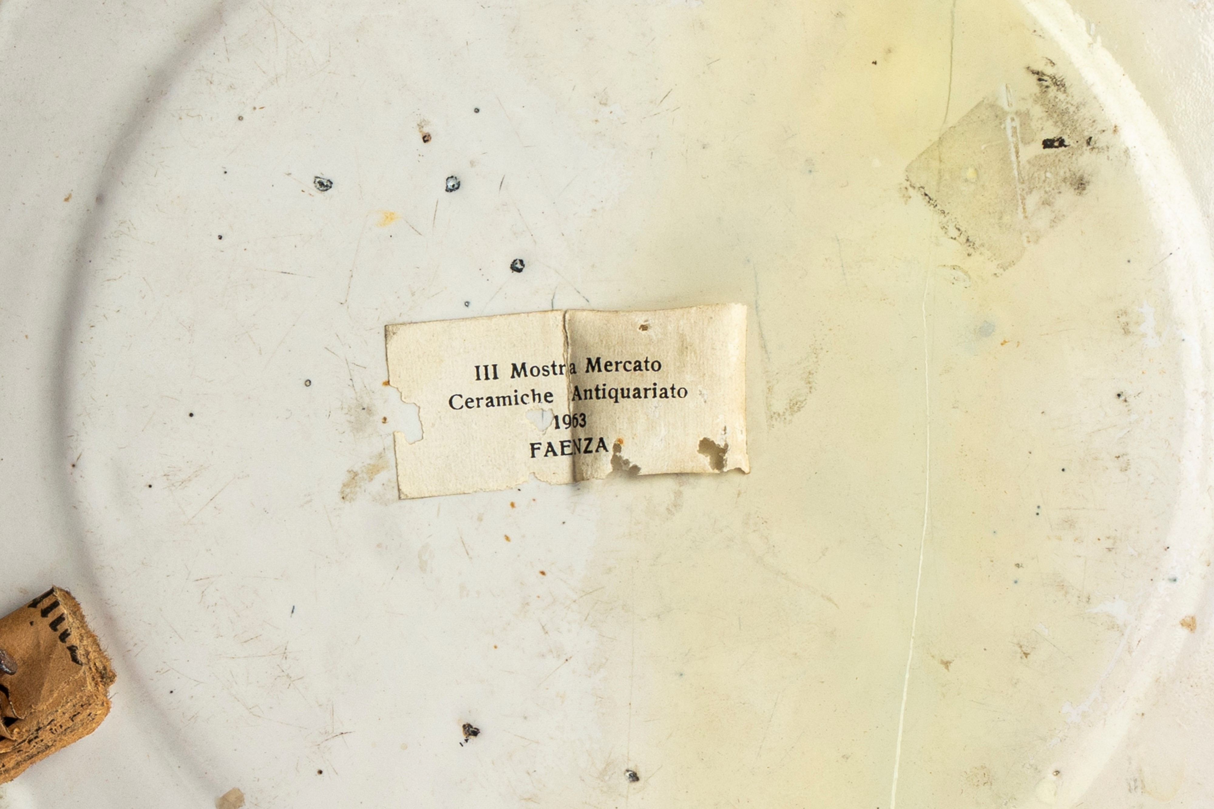 Piattello in maiolica policroma istoriata con putto alato musicante in un paesaggio agreste con s...