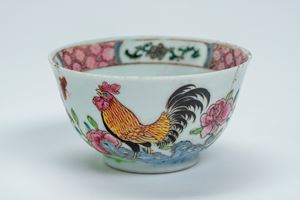 Tazzina in porcellana decorata a rilievo in policromia con gallo e farfalla su zolla erbosa con fiori. Cina, secolo XVIII