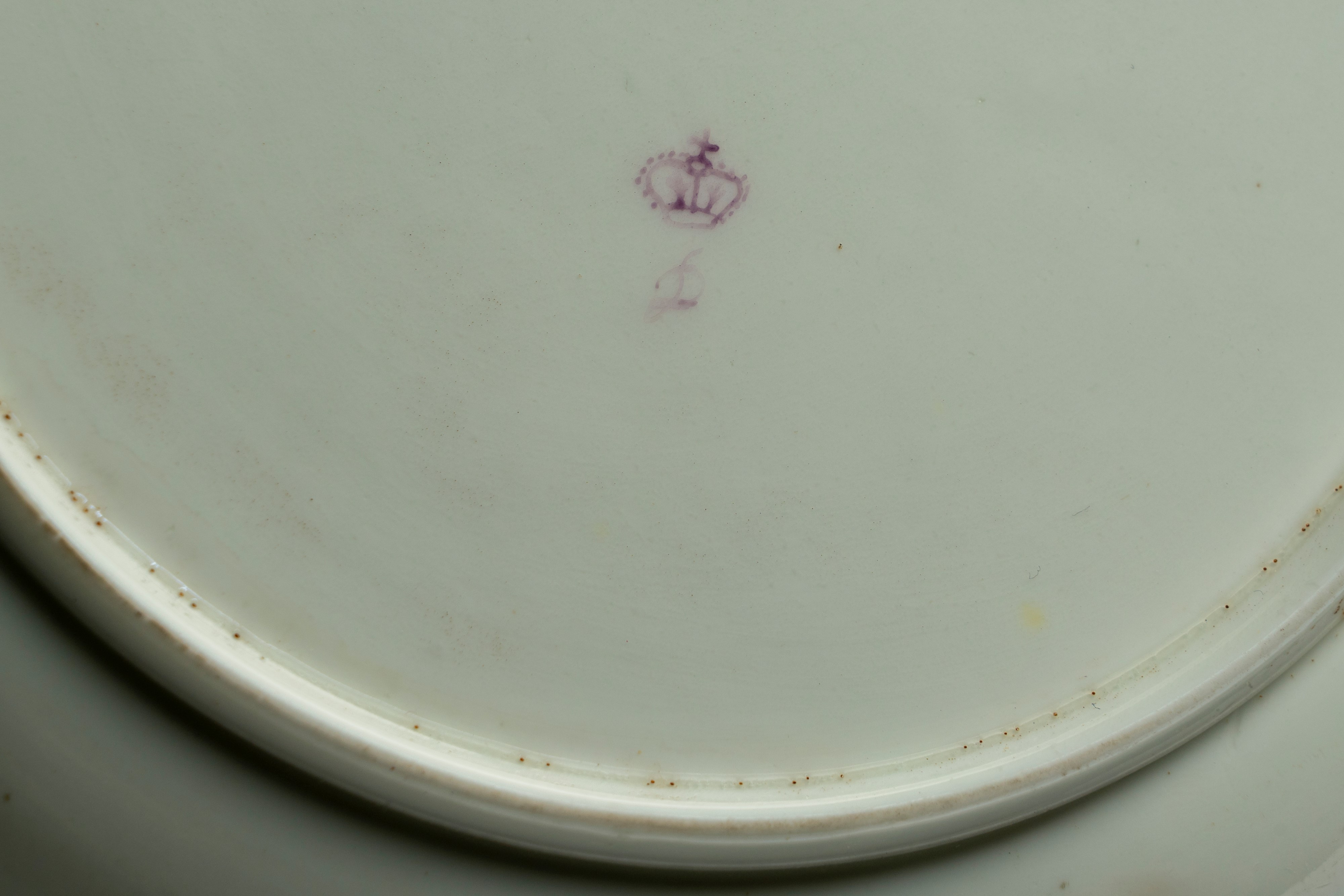 Porcellana, Piatto a profilo mosso e dorato con decoro policromo alla rosa e ghirlanda intrecciat...