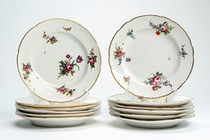 Twelve porcelain dinner plates with shaped and gilt rim, decorated in polychrome with central bouquet and scattered floral sprigs. Probably France, late 18th century