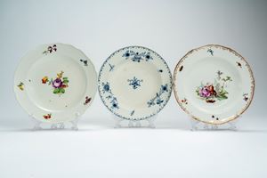Tre piatti in porcellana uno con decoro bianco-blu a motivi floreali, uno al mazzetto e fiori sparsi, l'altro a bordo mosso e dorato con scena galante tra fiori e insetti. Vienna, fine secolo XIX