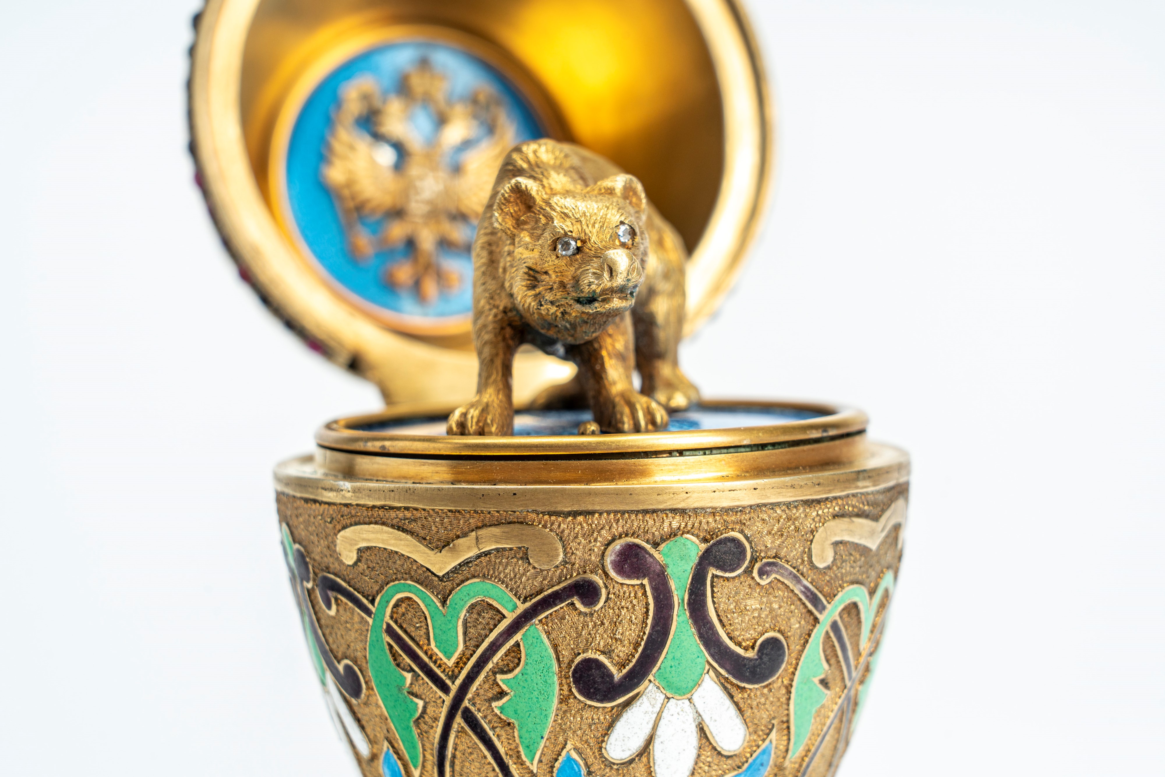 Uovo sormontato da corona in argento dorato, cesellato con smalti policromi cloisonné e guilloché...