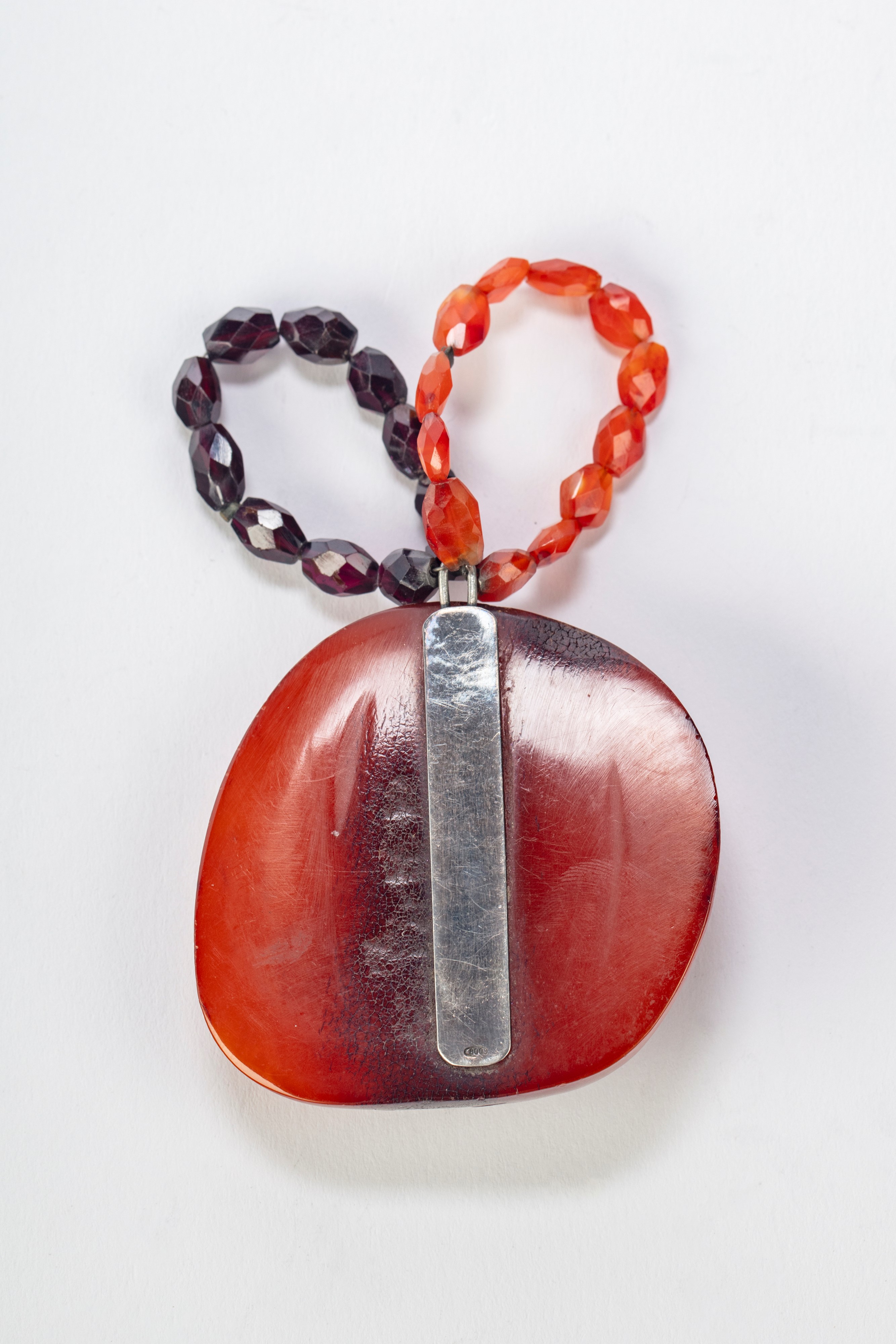 Ciondolo in ambra scolpito con uccellino su ramo fiorito. Cina, inizi secolo XX.