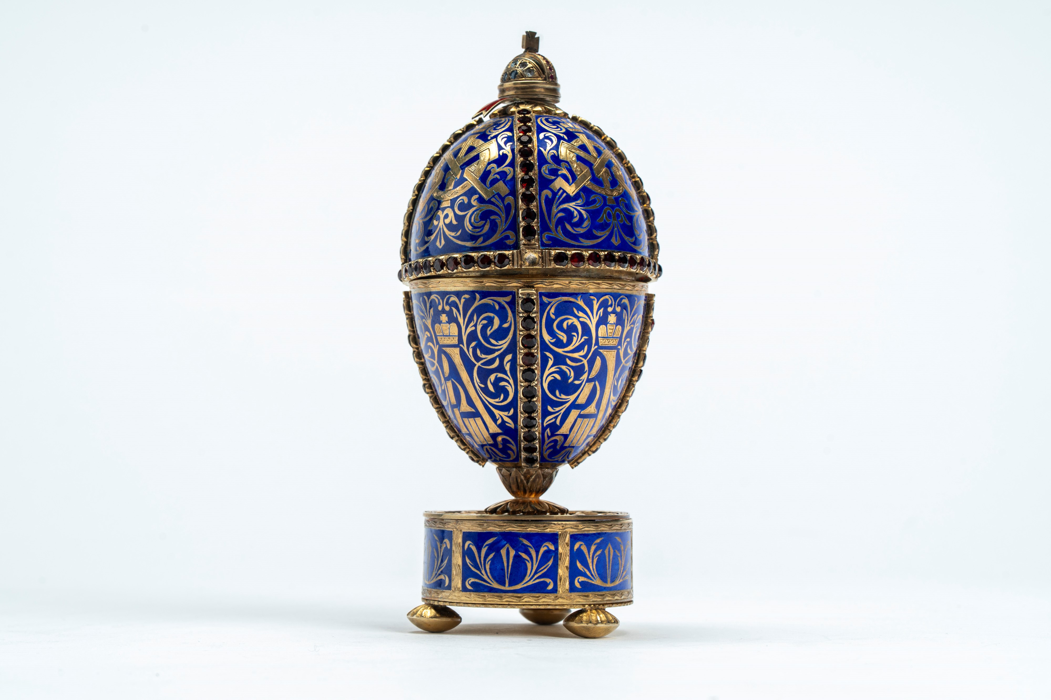 Uovo in argento dorato e smaltato a fondo blu, poggiante su base circolare con tre piedini. San P...