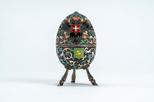 Uovo in argento dorato con smalti policromi cloisonné e cabochon, coperchio apribile decorato con aquila bicipite coronata con scettro e globo e piccolo scudo centrale, poggiante su tre piedi a zampa caprina. Mosca, inizio secolo XX