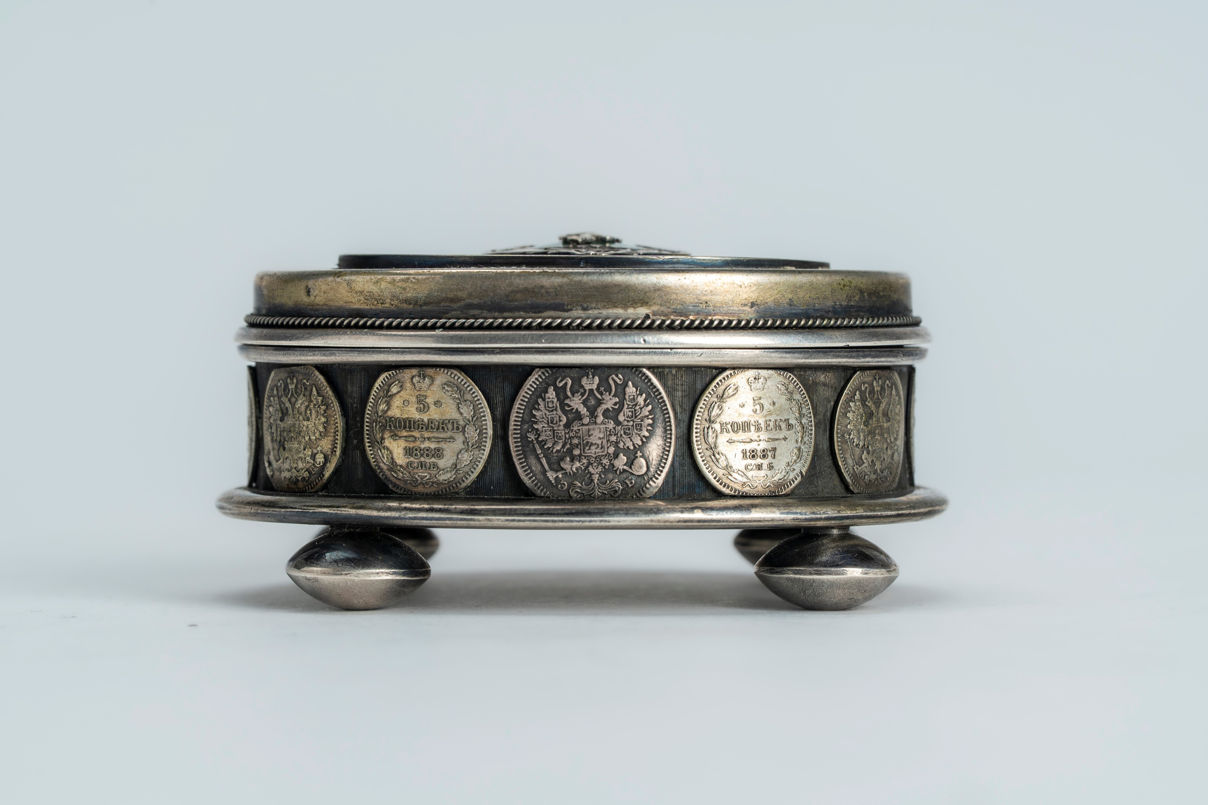 Scatola con coperchio in argento e smalti guilloché verde e blu con fascia di monetine incassate....