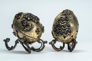 Due uova con coperchio in argento e cabochon una decorata a rilievo con pavone e l’altra con putti e ghirlande di fiori. Russia, fine XIX secolo