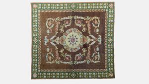 Tappeto a fondo marrone con bordura in verde riccamente decorato a motivi floreali. Secolo XX