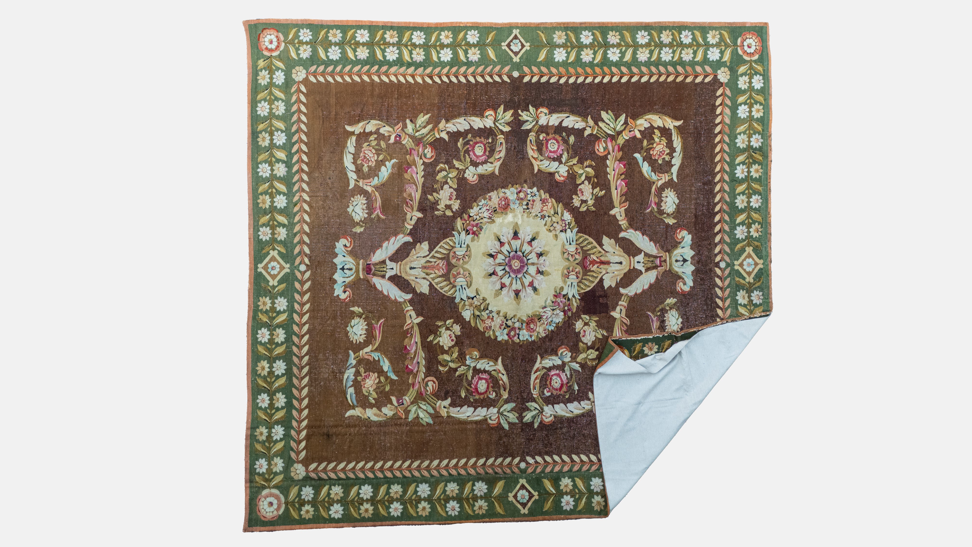 Tappeto a fondo marrone con bordura in verde riccamente decorato a motivi floreali. Secolo XX