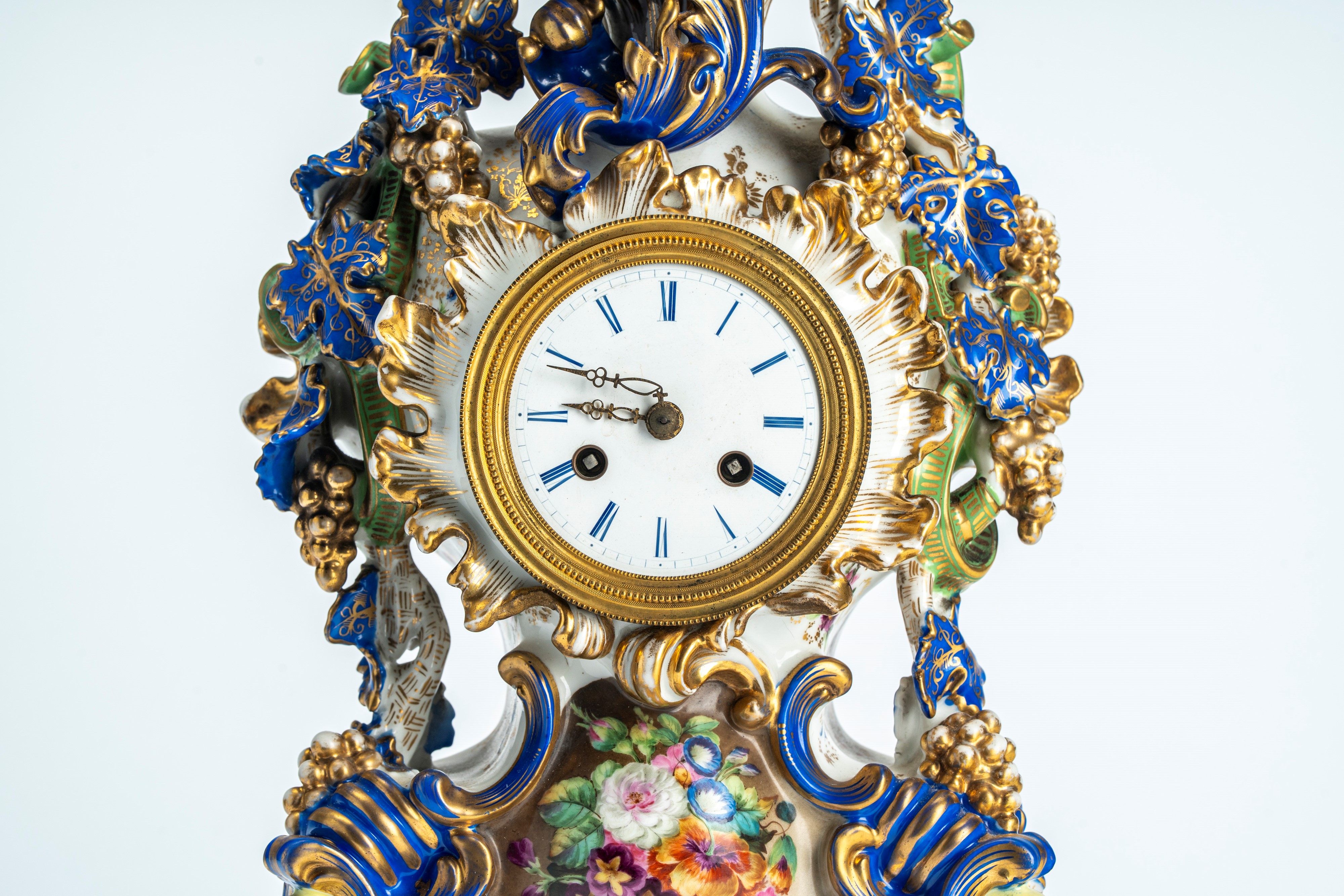 Pendola di forma mossa in porcellana policroma e dorata riccamente decorata a tralci di vite, pog...