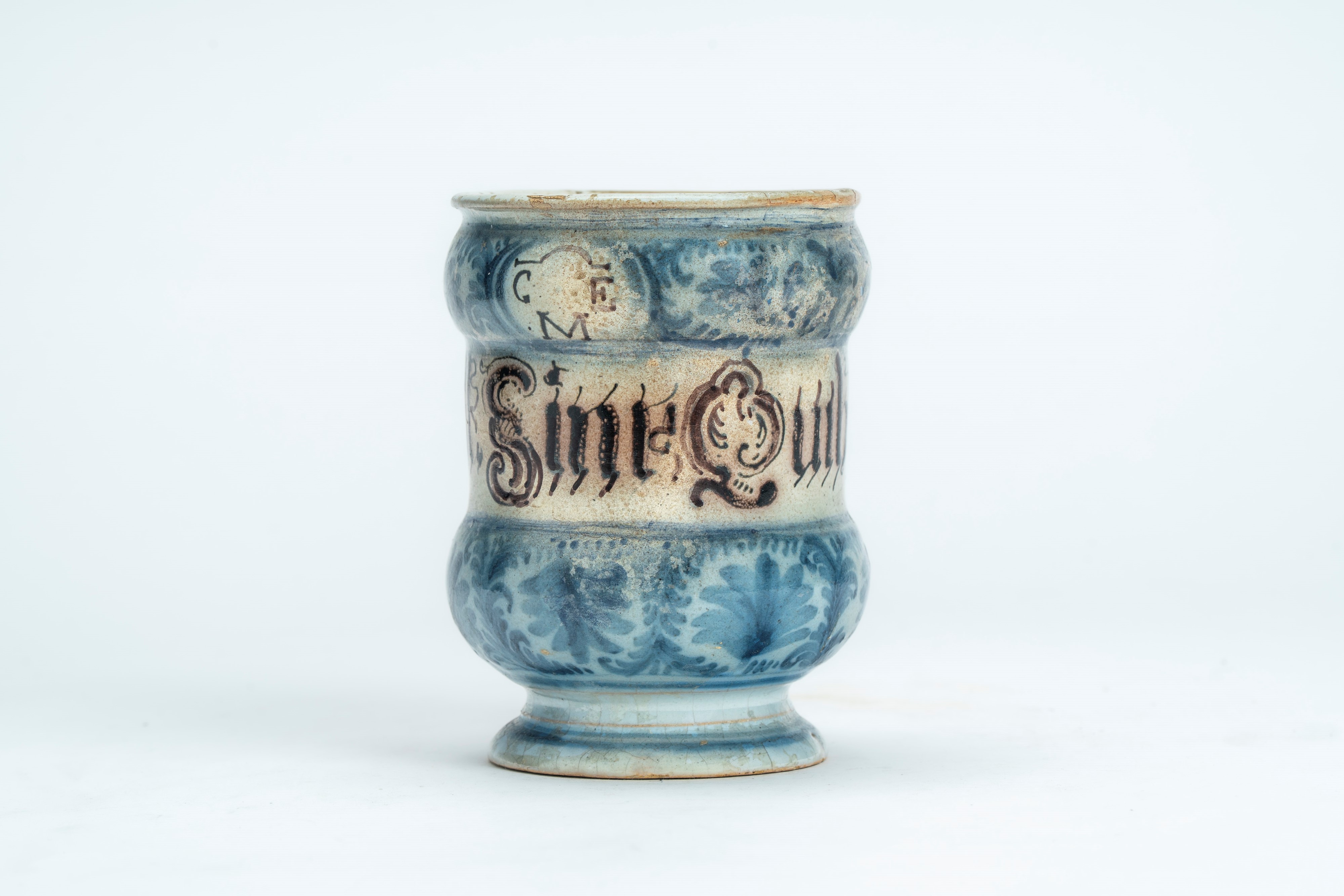 Albarello in maiolica con decoro blu cobalto a motivi vegetali interrotto da cartiglio con scritt...