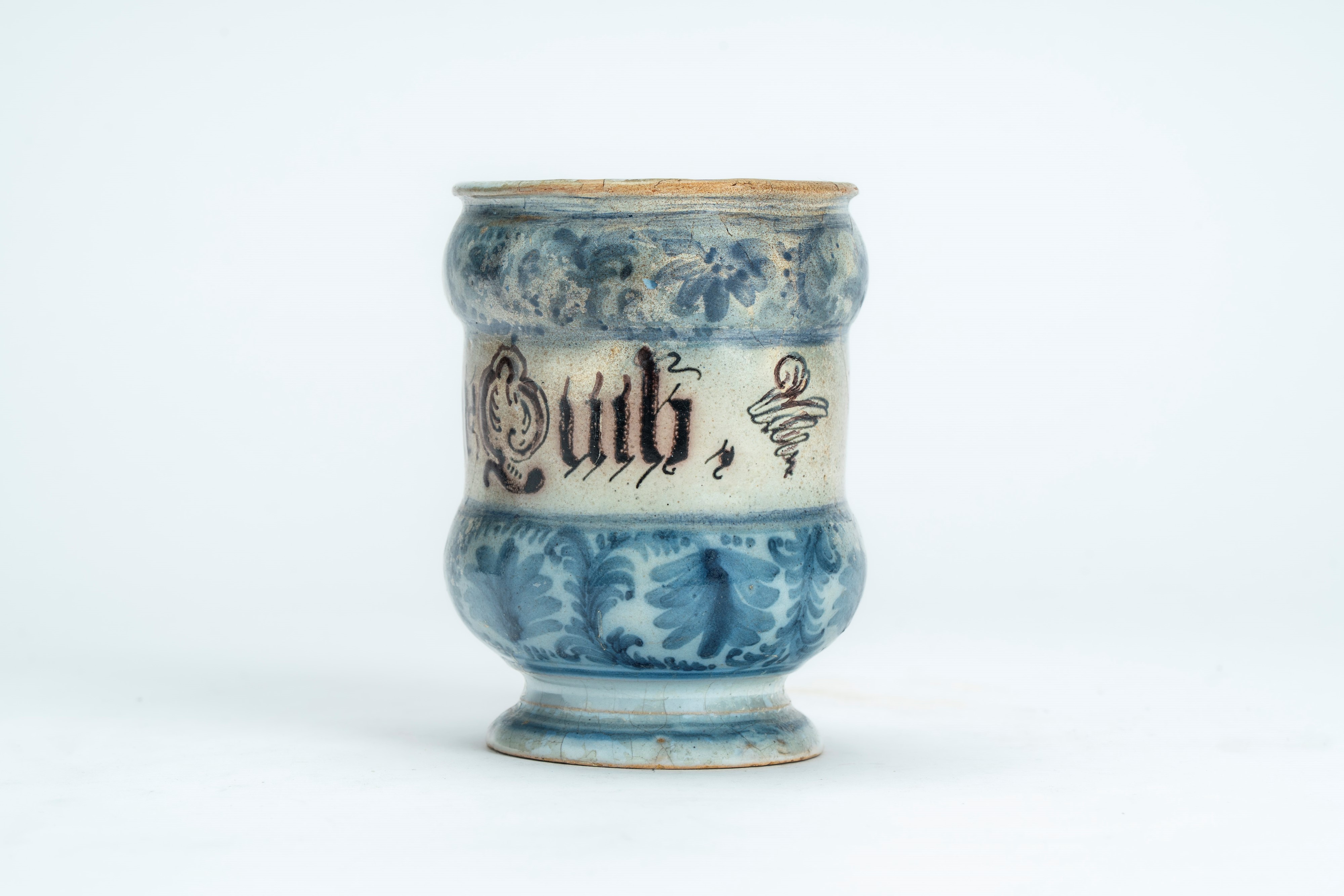 Albarello in maiolica con decoro blu cobalto a motivi vegetali interrotto da cartiglio con scritt...