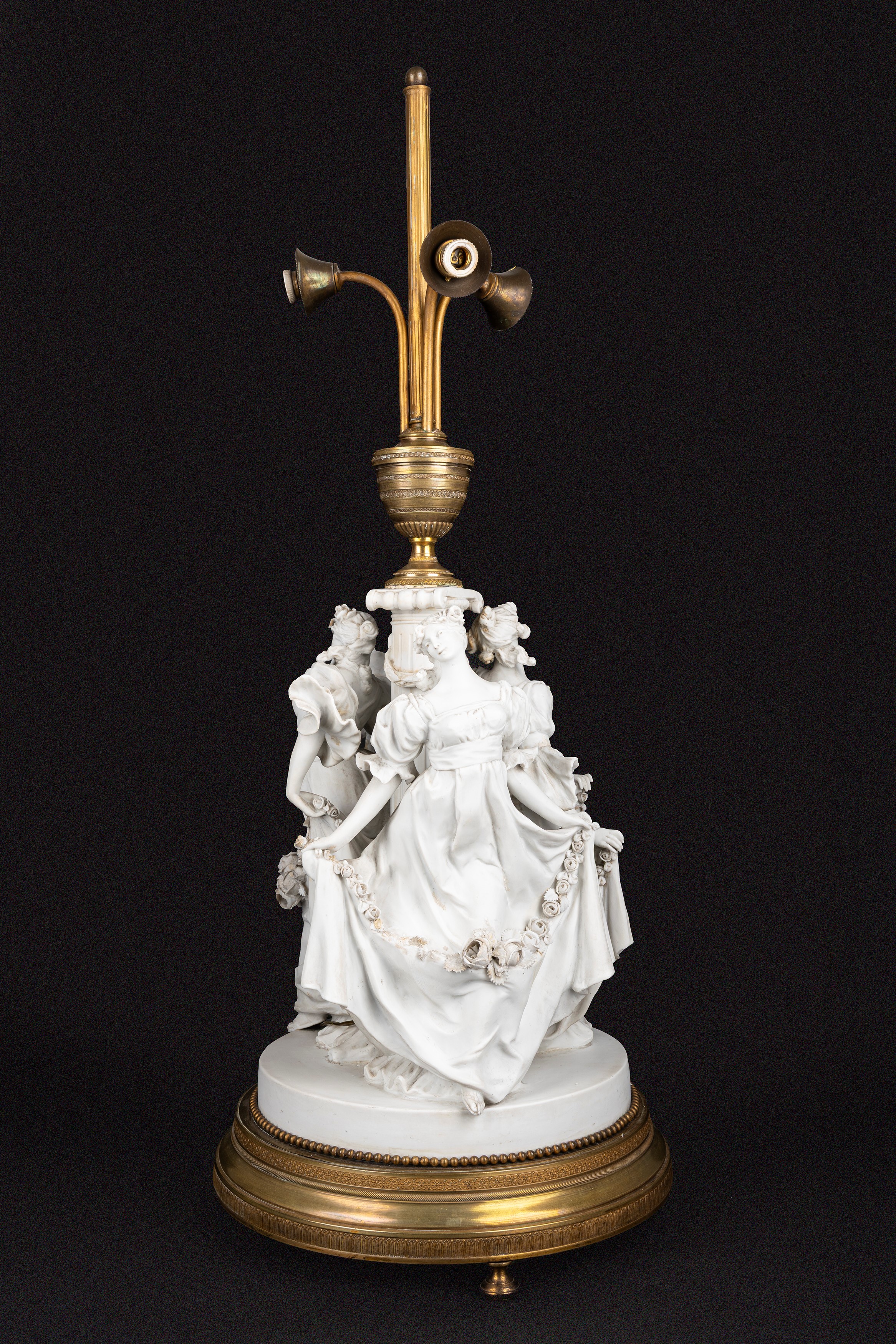 Lampada da tavolo in biscuit e bronzo dorato, con fusto con tre fanciulle danzanti e ghirlande di...