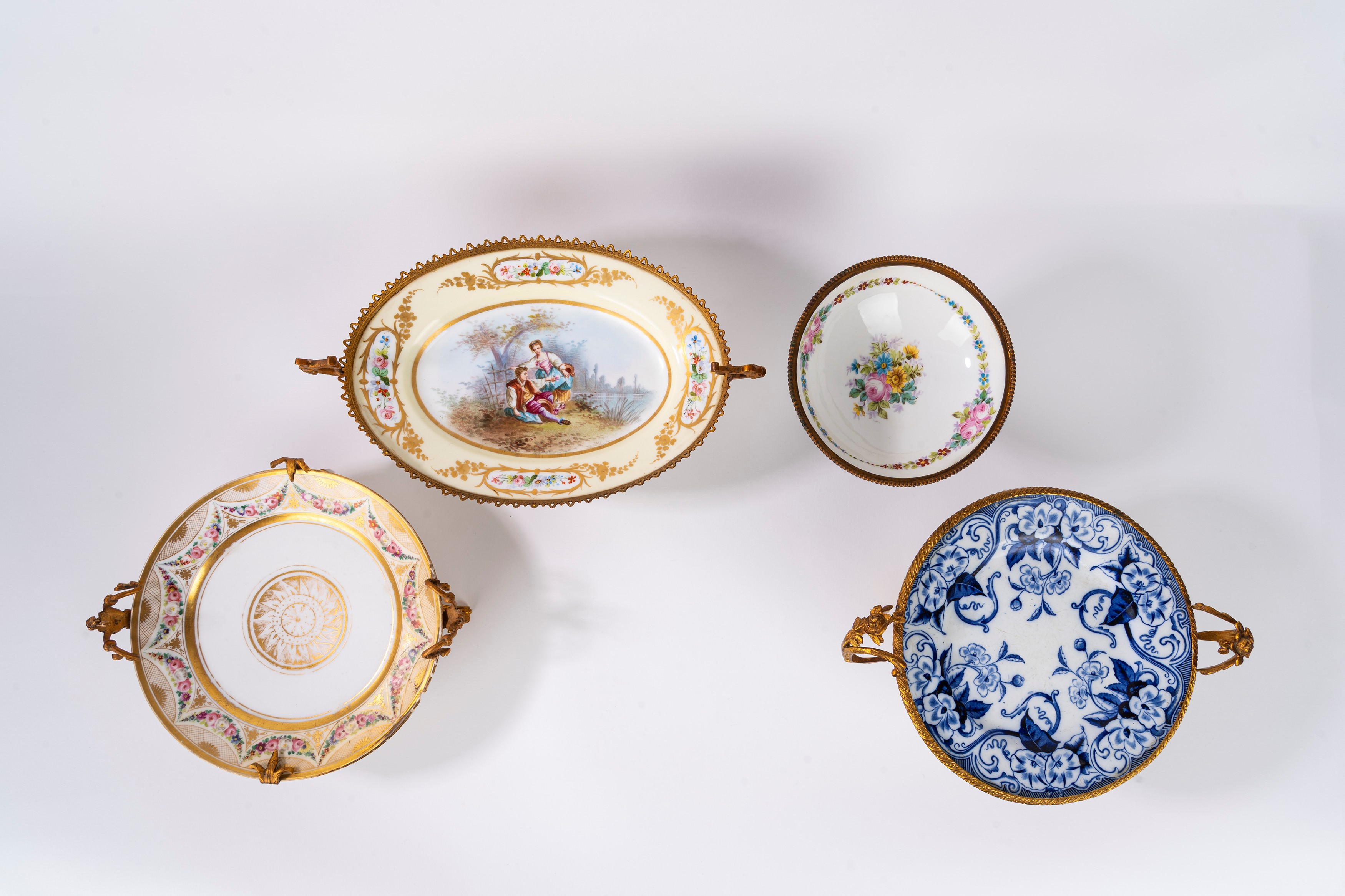 Tre piatti e un’alzatina in porcellana policroma con montatura in bronzo dorato, Francia