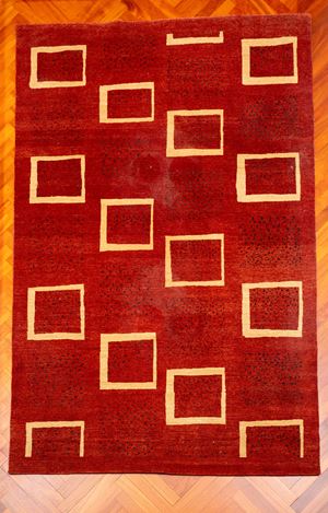 Tappeto a campo color ruggine, decorato da motivi geometrici quadrangolari color avorio disposti in sequenza regolare. Fine secolo XX/inizio XXI