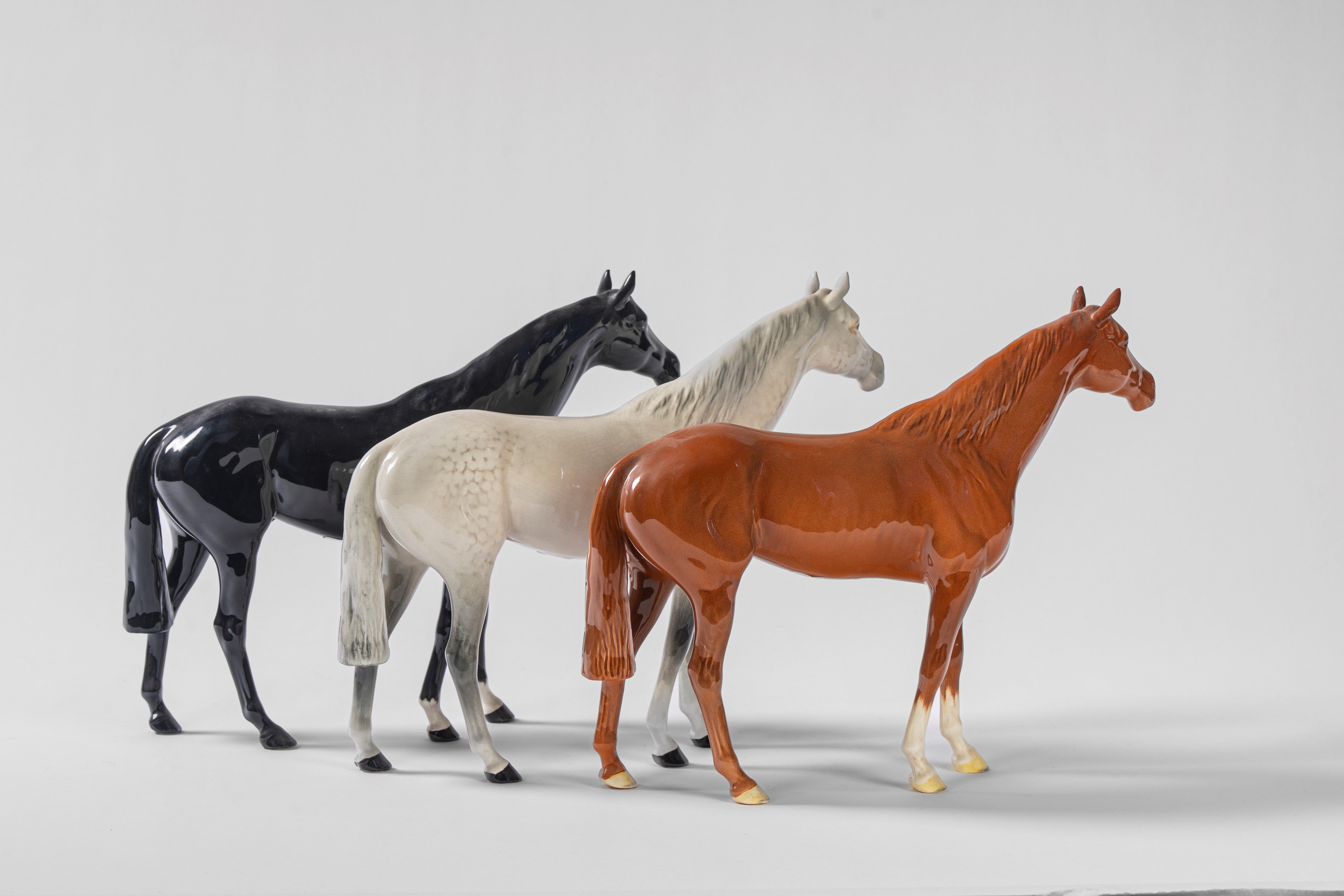 Tre cavalli da corsa in porcellana policroma. Beswick, Inghilterra, secolo XX