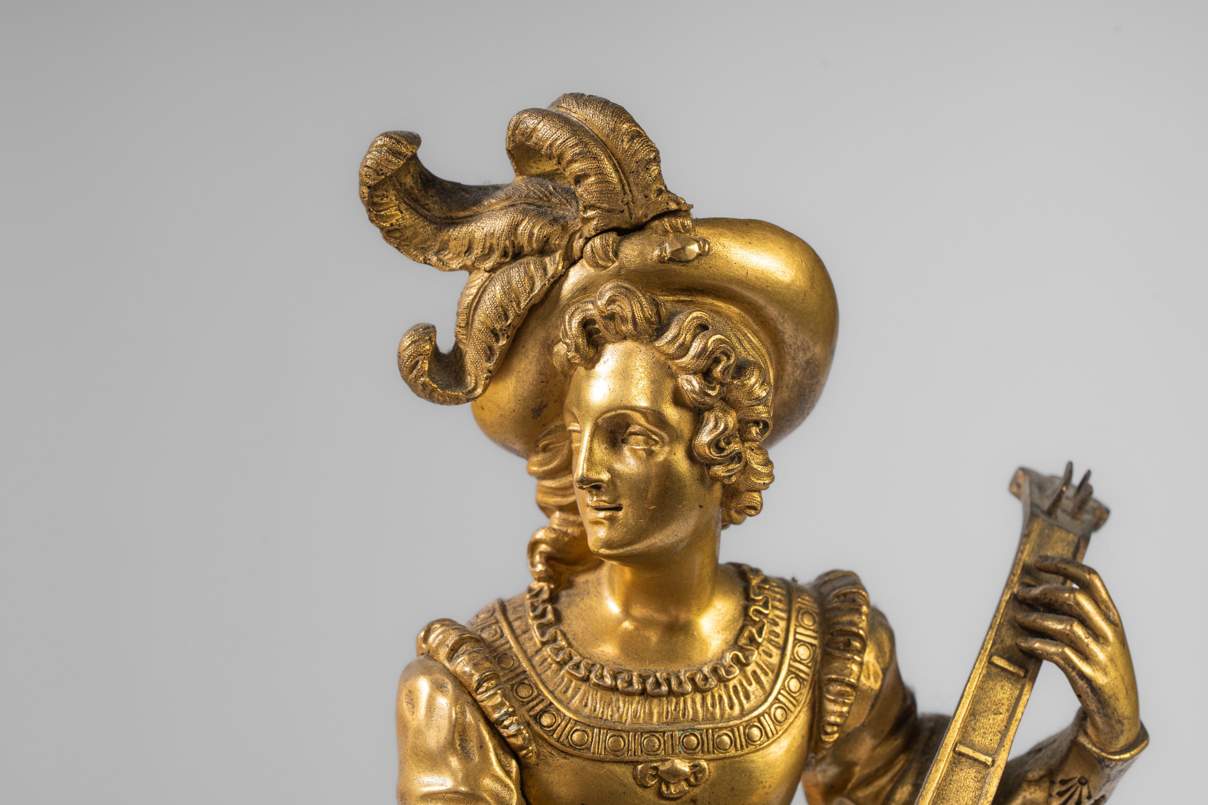 Pendola da appoggio in bronzo dorato e patinato con suonatore di liuto, Francia, primo quarto XIX...