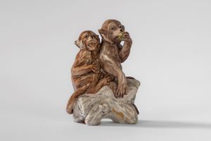 Due scimmiette sedute su un tronco, piccolo gruppo in porcellana policroma.