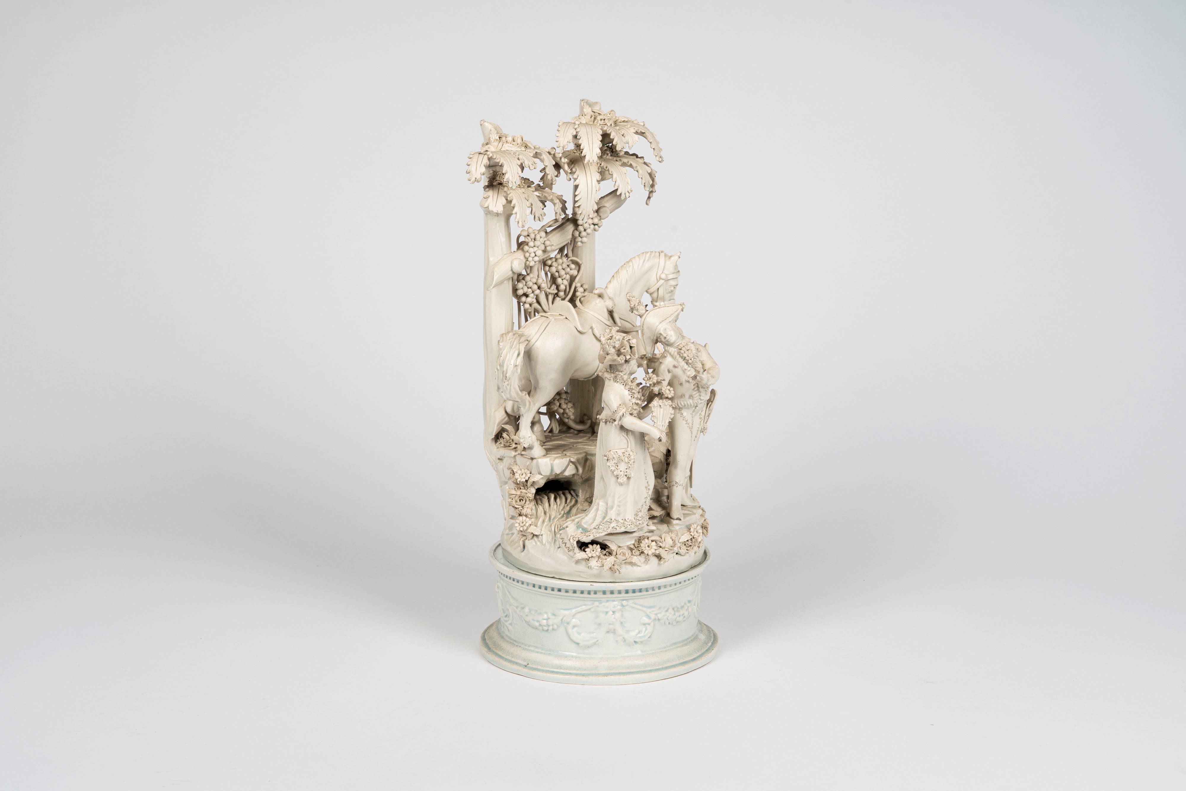 Gruppo in terraglia smaltata bianca raffigurante scena galante in un giardino con cavallo e giova...