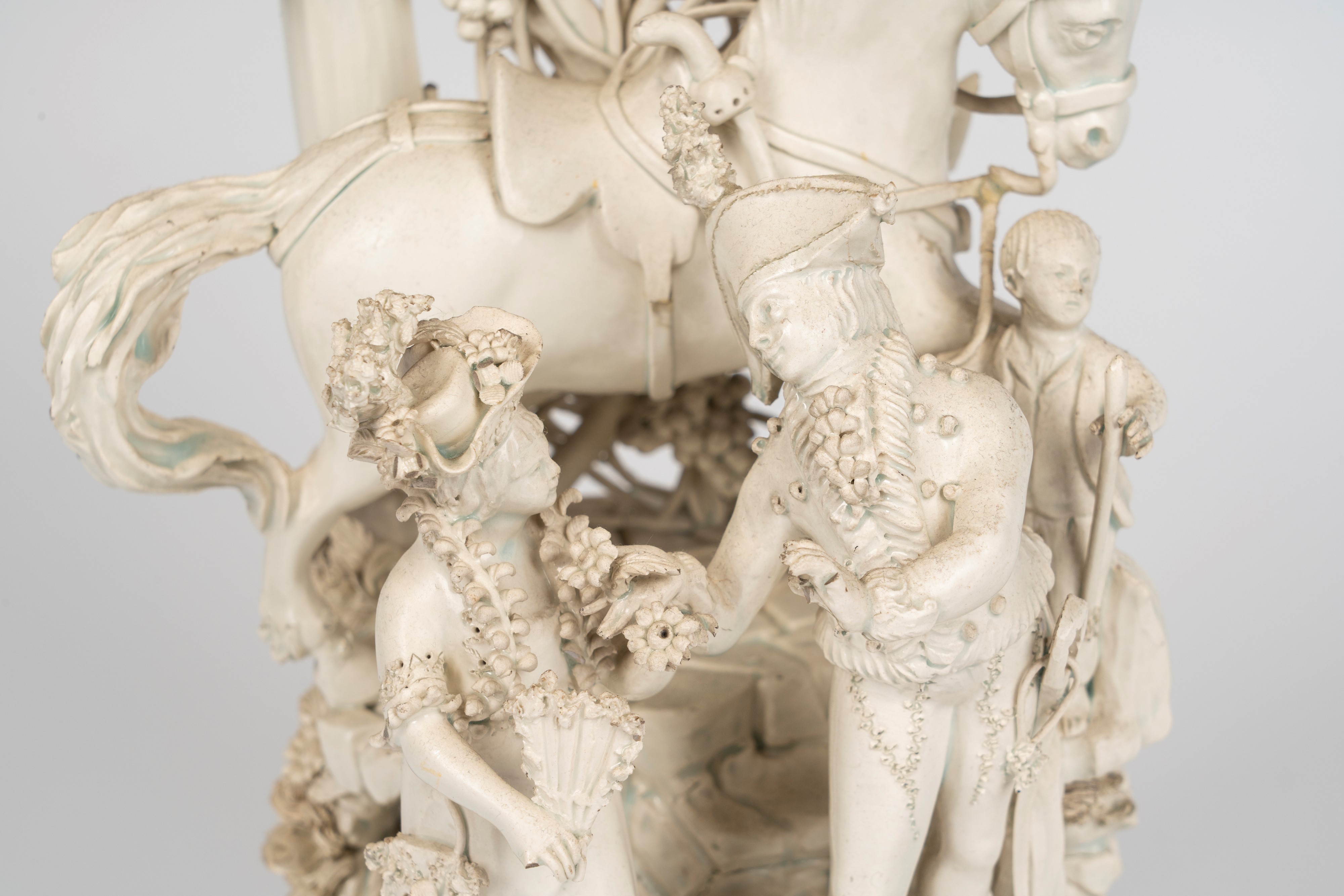 Gruppo in terraglia smaltata bianca raffigurante scena galante in un giardino con cavallo e giova...