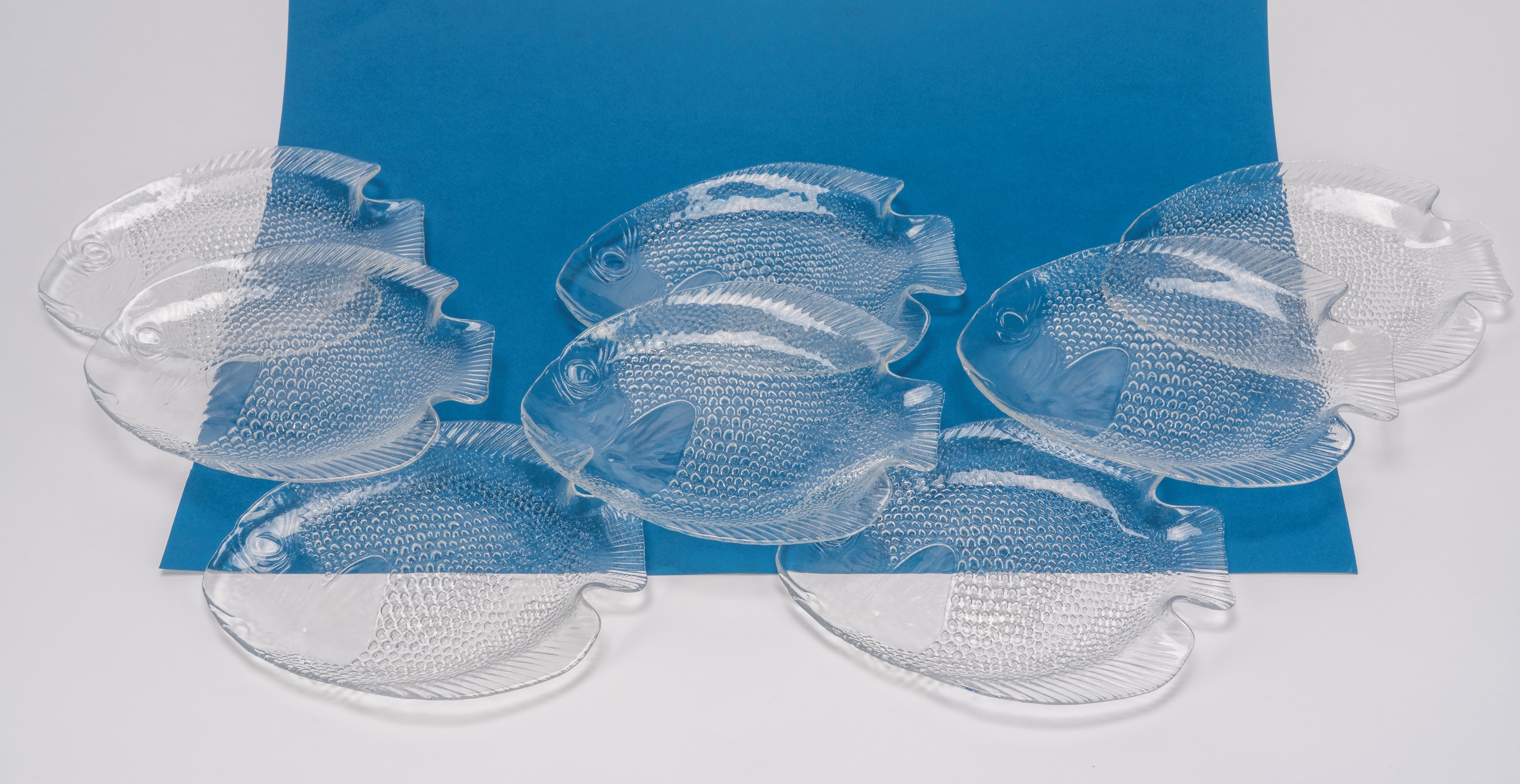 Set di otto piattini in vetro trasparente a forma di pesce, decoro squamato a rilievo