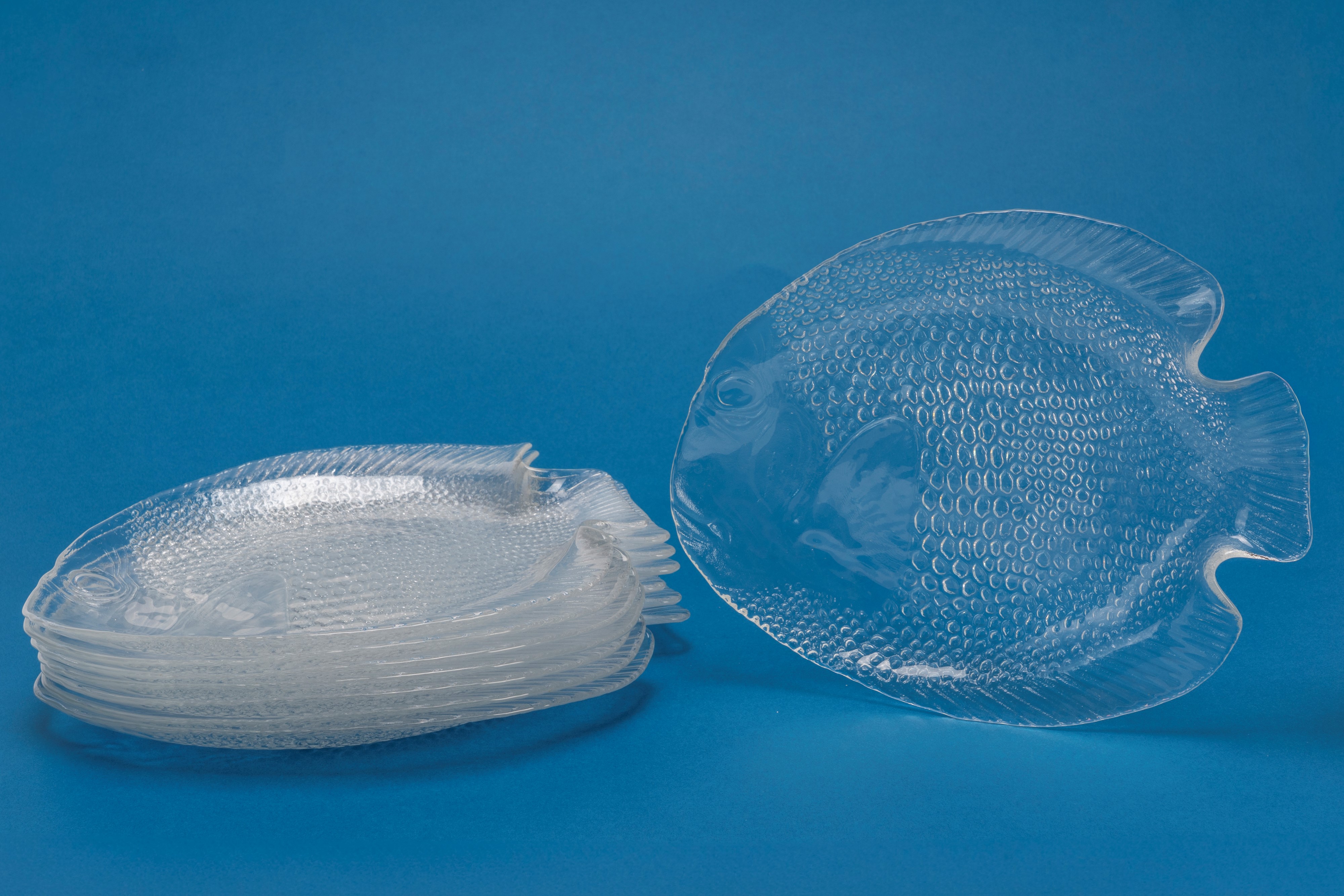 Set di otto piattini in vetro trasparente a forma di pesce, decoro squamato a rilievo