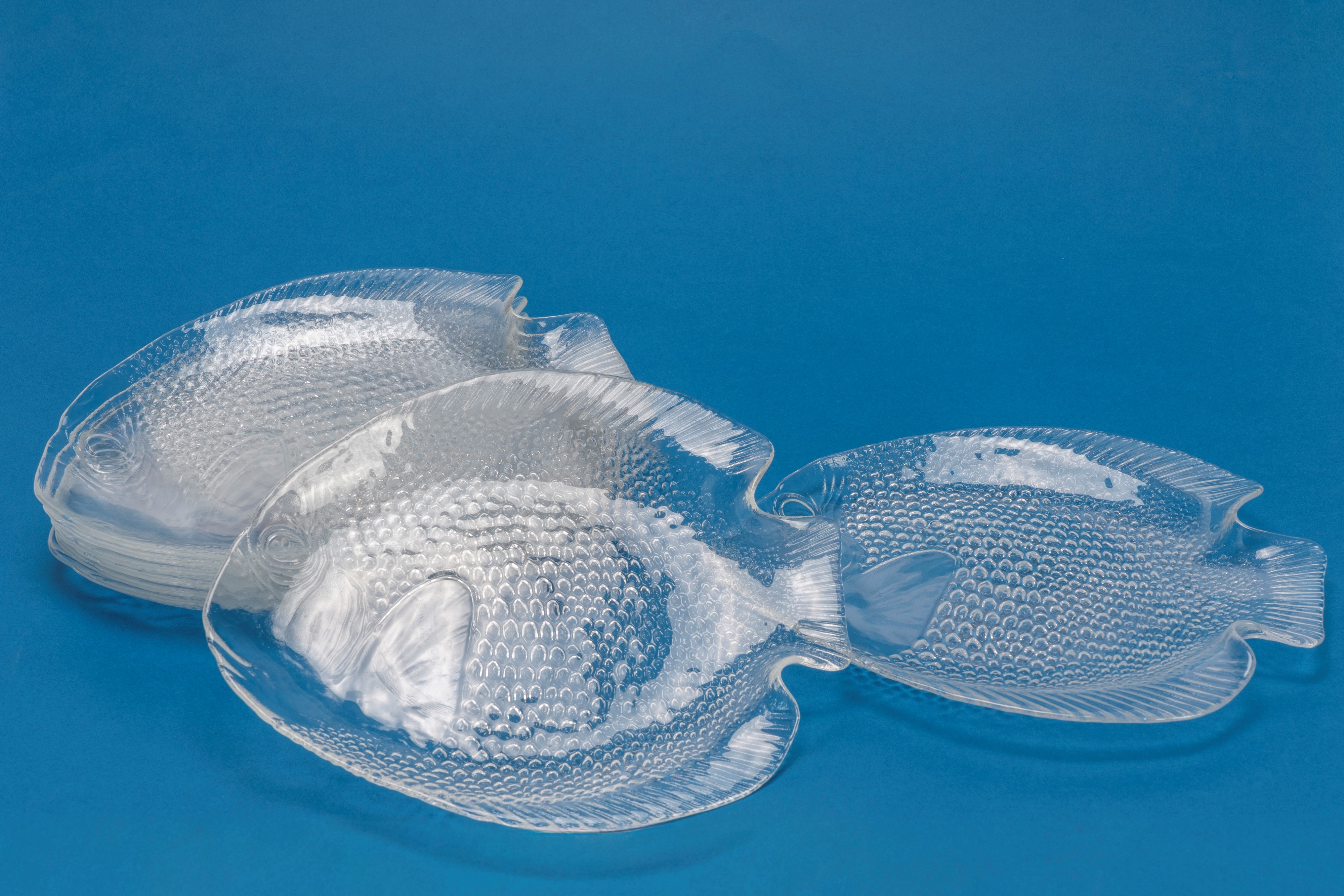 Set di otto piattini in vetro trasparente a forma di pesce, decoro squamato a rilievo