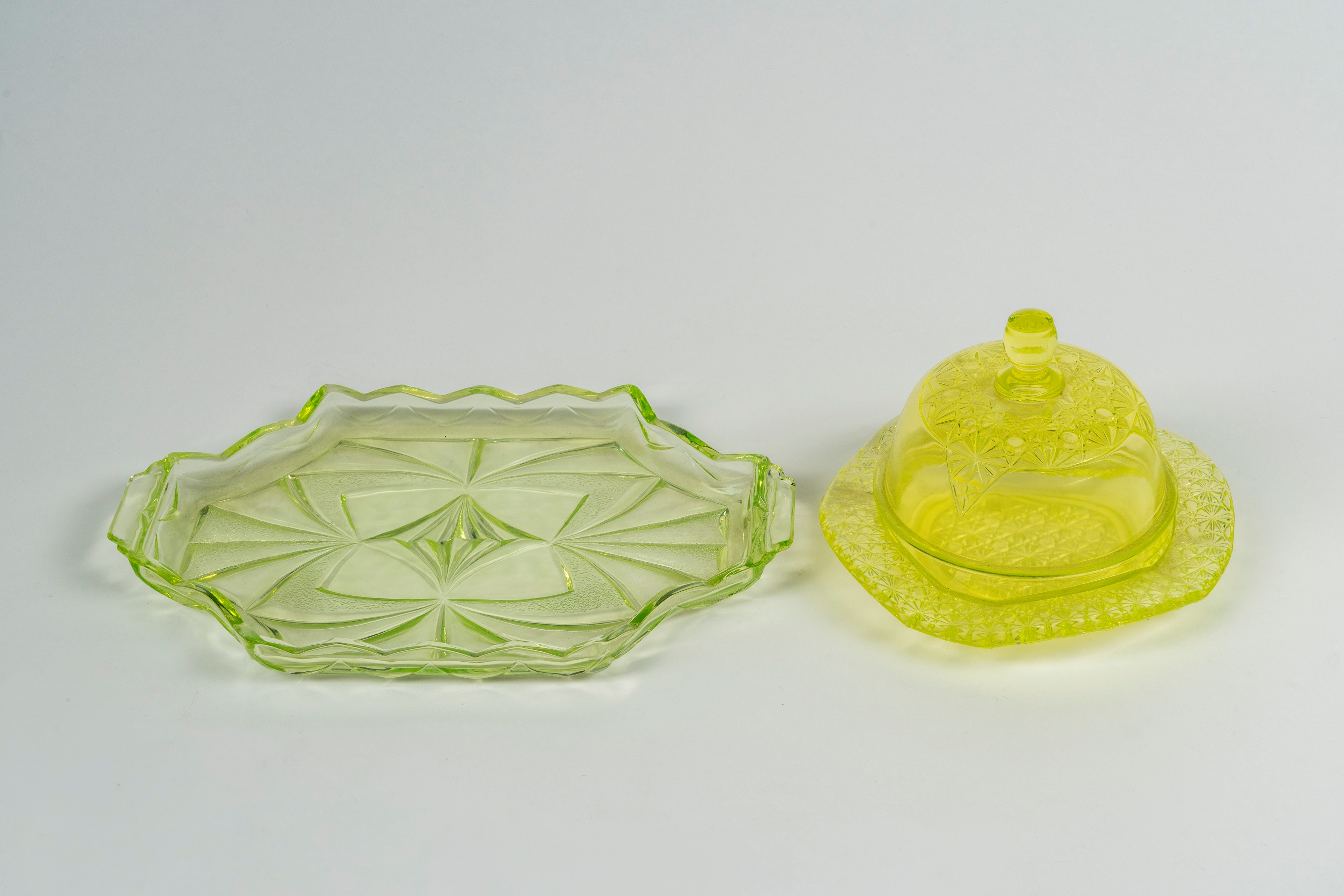 Lotto composto da un vassoio biansato di forma mossa e una burriera con coperchio in vetro verde ...