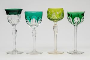 Four different glasses in clear crystal and in shades of green, three resting on a circular base and one on a hexagonal base