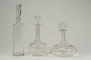 Lot consisting of a Lalique France clear glass decanter and two bottles, one with a cylindrical stopper and the other with a high fluted neck and disc stopper.