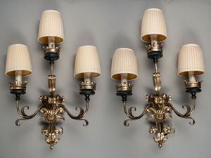 Pair of three-light silver metal wall lamps with arms decorated with scrolls of leaves and flowers
