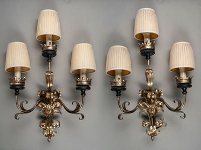 Coppia di appliques, metallo argentato a tre luci con bracci mossi a volute di foglie e fiori