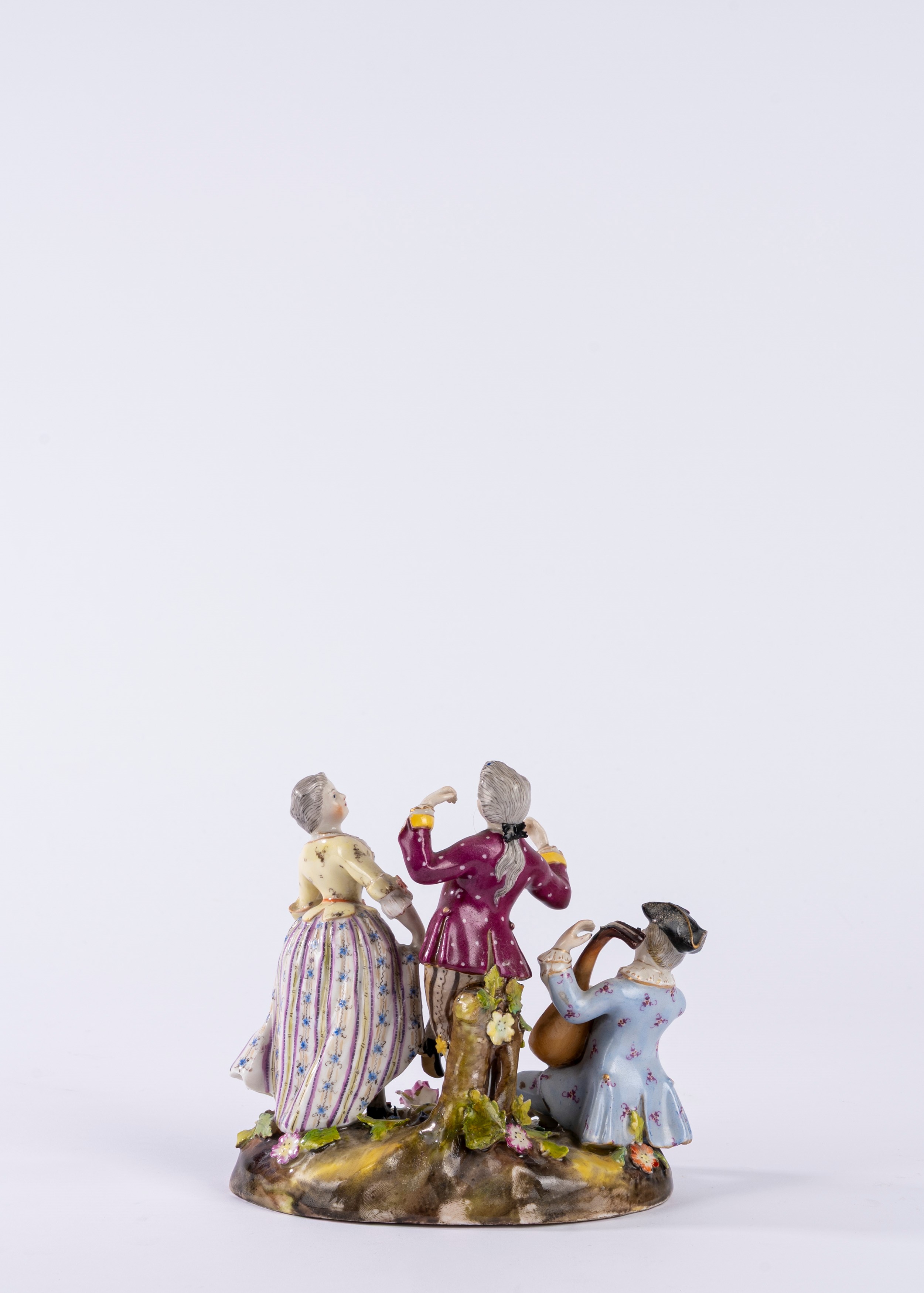 Gruppo in porcellana policroma raffigurante scena galante con suonatore di chitarra su zolla erbo...