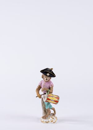 Figura in porcellana policroma raffigurante scimmietta musicante con tamburo, su base a rocaille. Fine secolo XIX/XX.