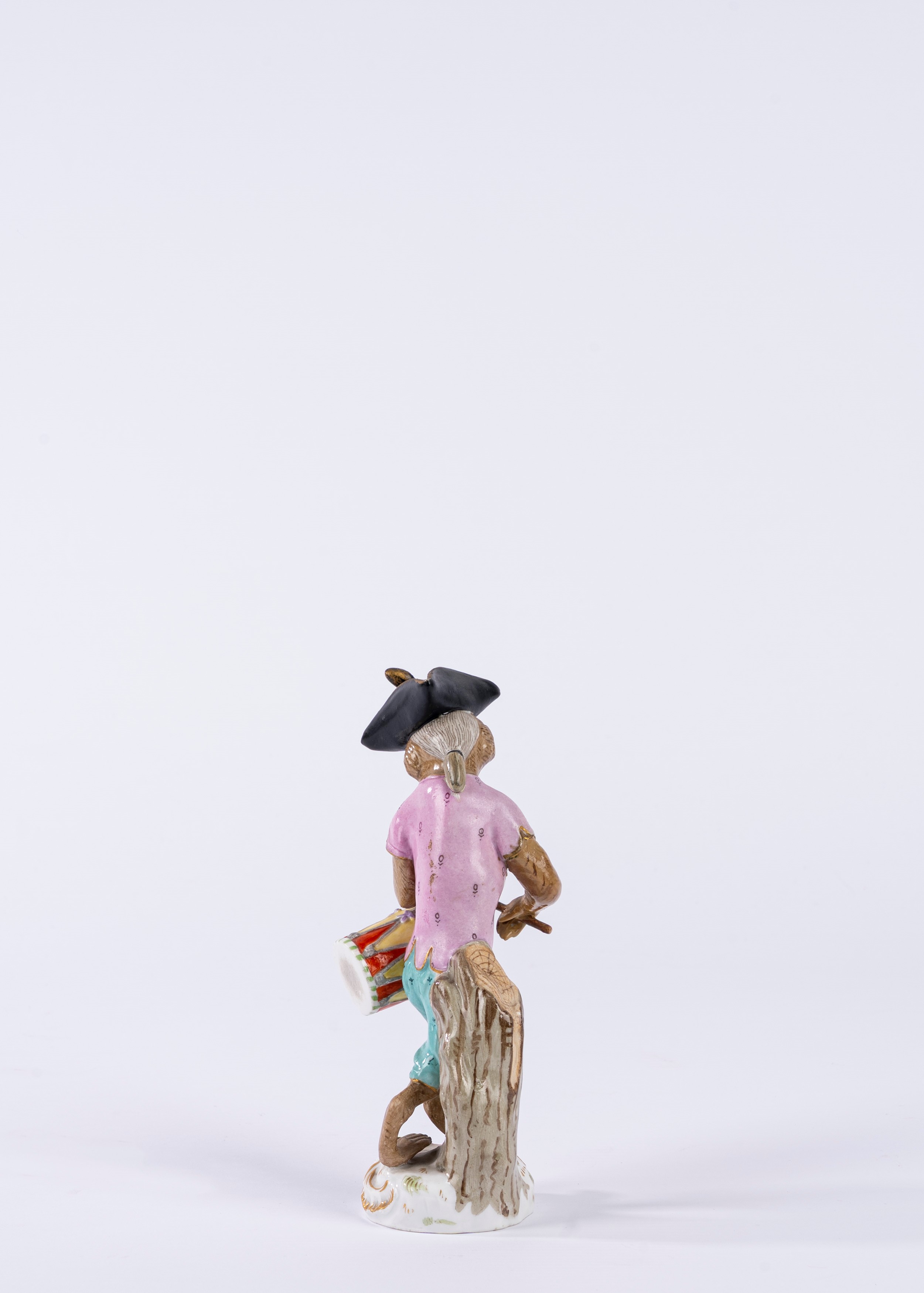 Figura in porcellana policroma raffigurante scimmietta musicante con tamburo, su base a rocaille....