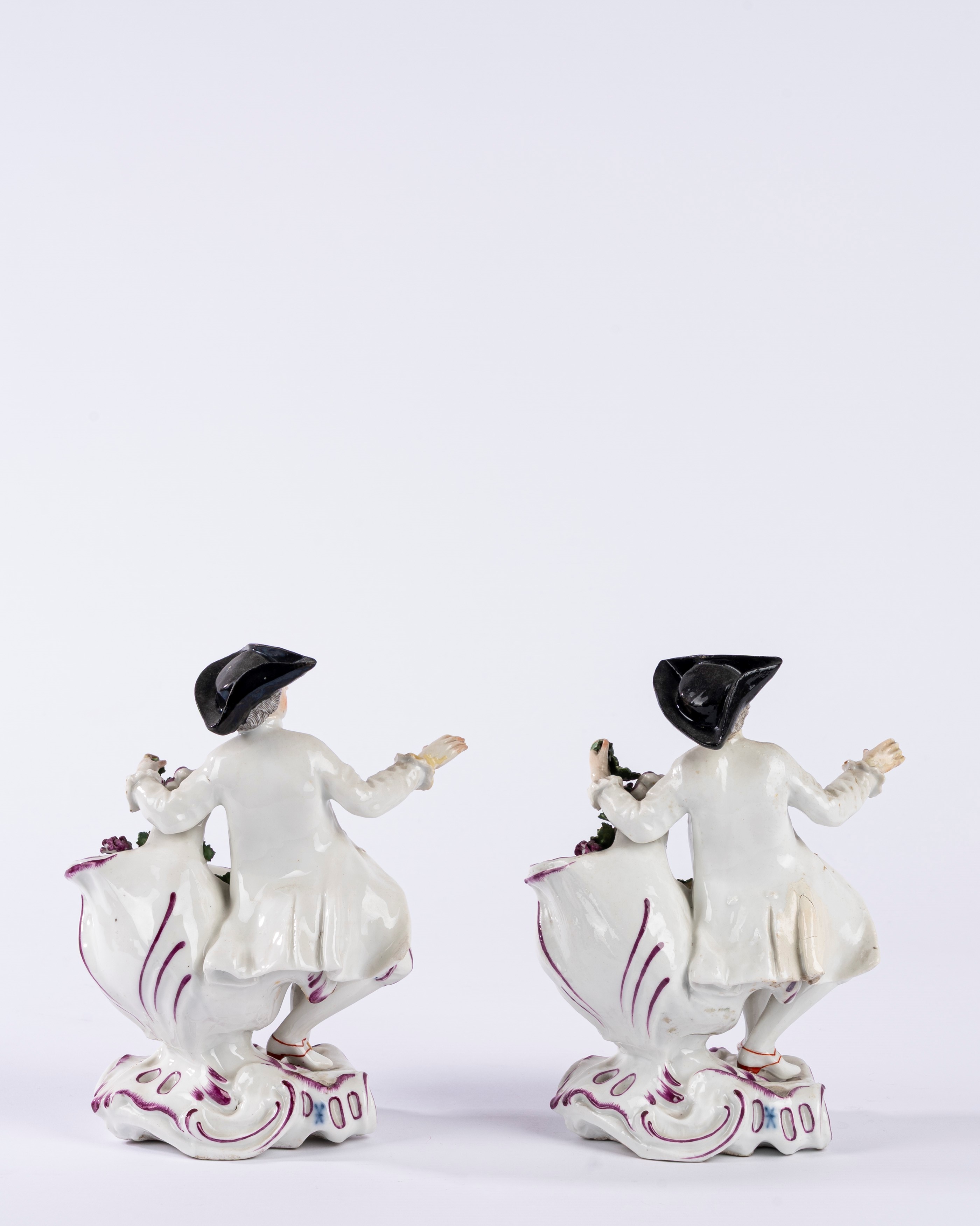 Coppia di saliere in porcellana policroma in forma di gentiluomo, su base a rocaille. Manifattura...