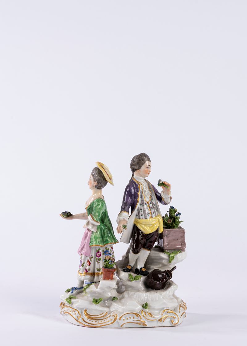 Gruppo in porcellana policroma raffigurante due figure in un giardino, su base a rocaille. Manifa...