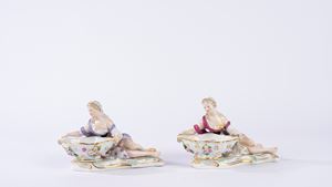Coppia di saliere o salsiere in porcellana policroma in forma di fanciulla sdraiata che sostiene una vaschetta decorata con fiori applicati in rilievo, su una base a rocaille. Manifattura di Meissen, fine secolo XIX/inizio secolo XX.